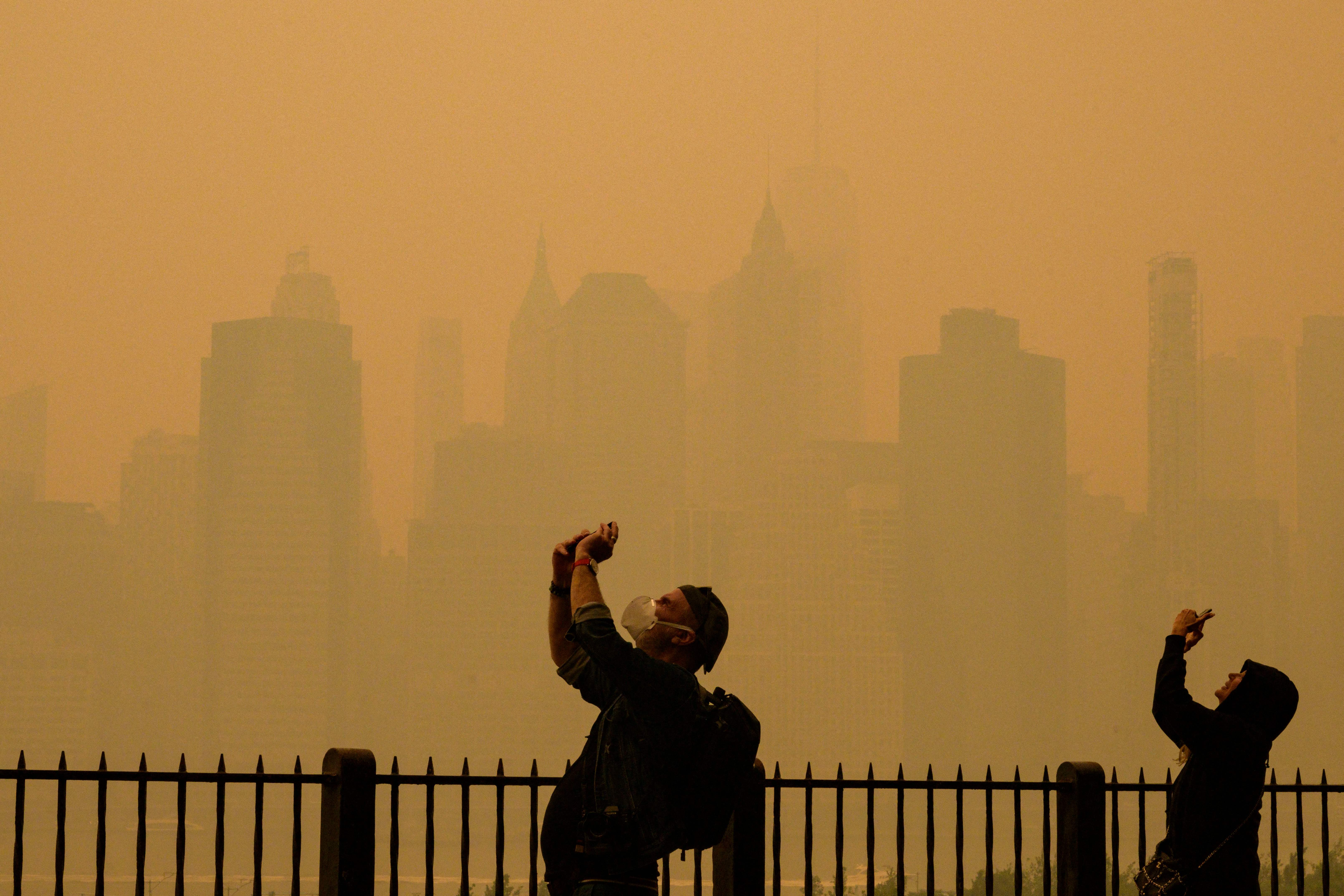 Two people take photos in a smoke-filled New York City. Air pollution may be triggering an immune response in infants that leads to nut allergies, the researchers revealed