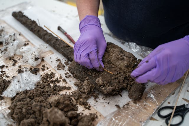 Experts from Wessex Archaeology carefully clean the spade of excess mud as part of the conservation process (Wessex Archaeology/PA)