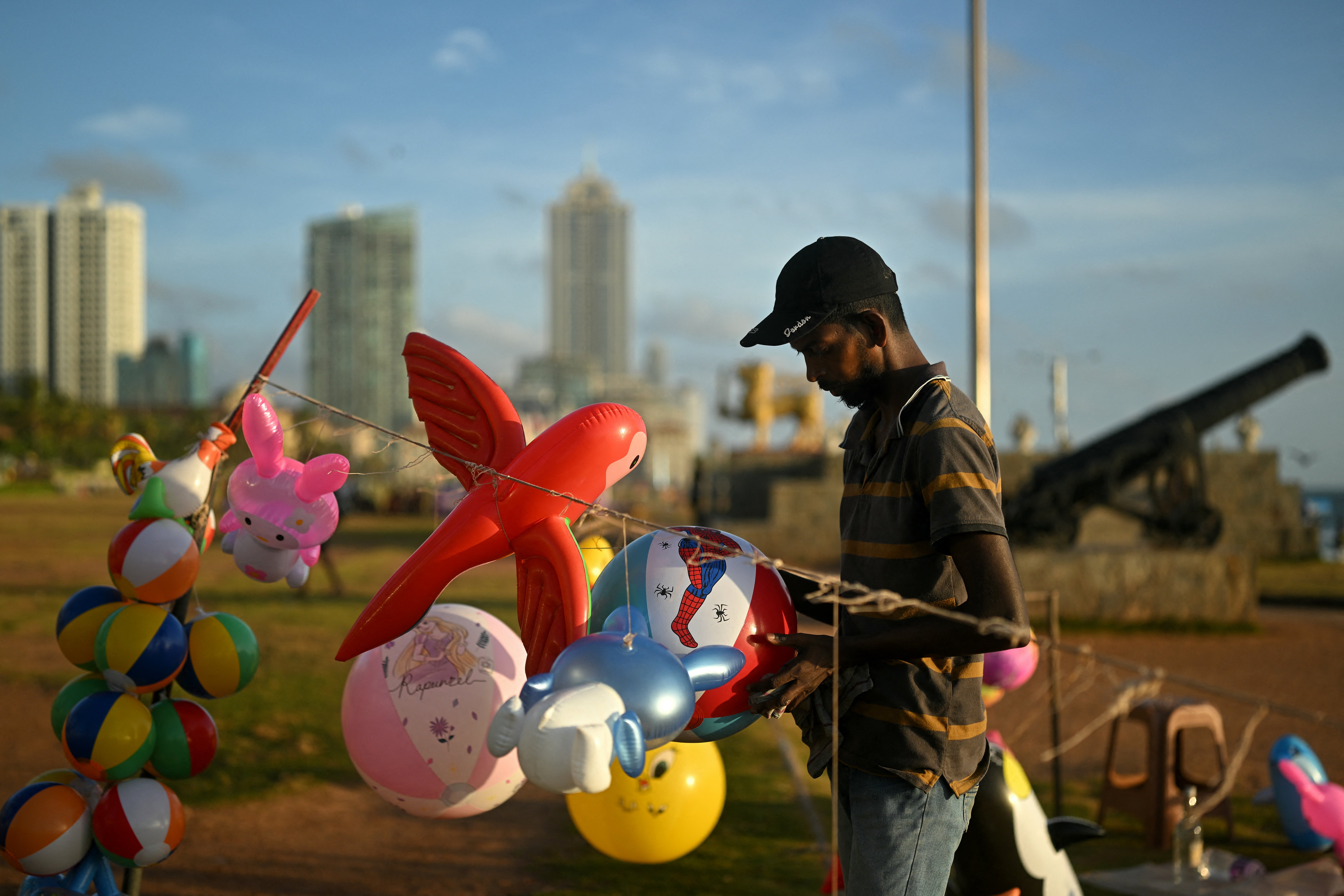 A vendor arranges inflated toys while waiting for customers at the Galle Face Beach during sunset in Colombo on September 24, 2024