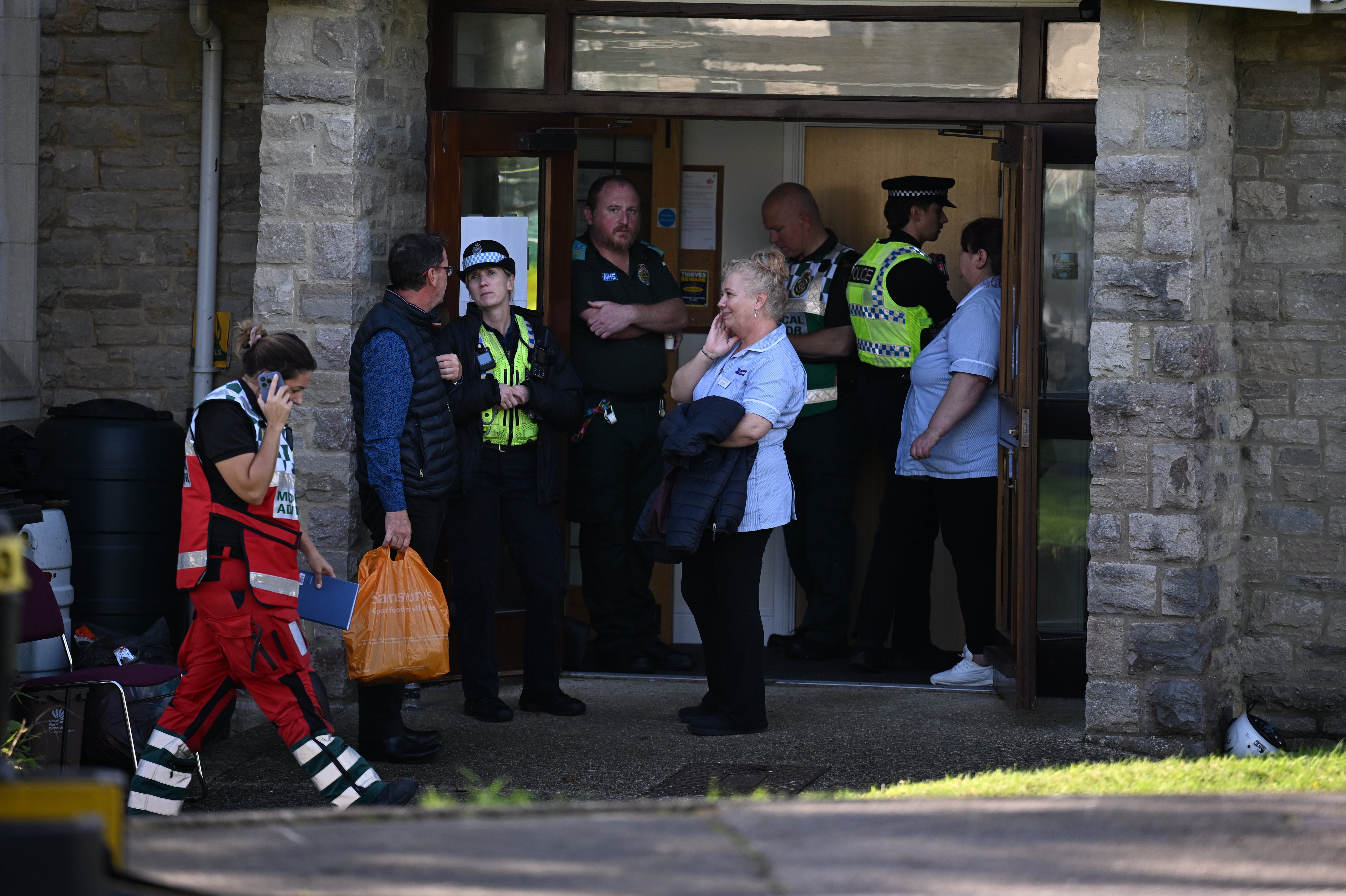 Staff and emergency services stand outside the All Saints church hall where residents were taken