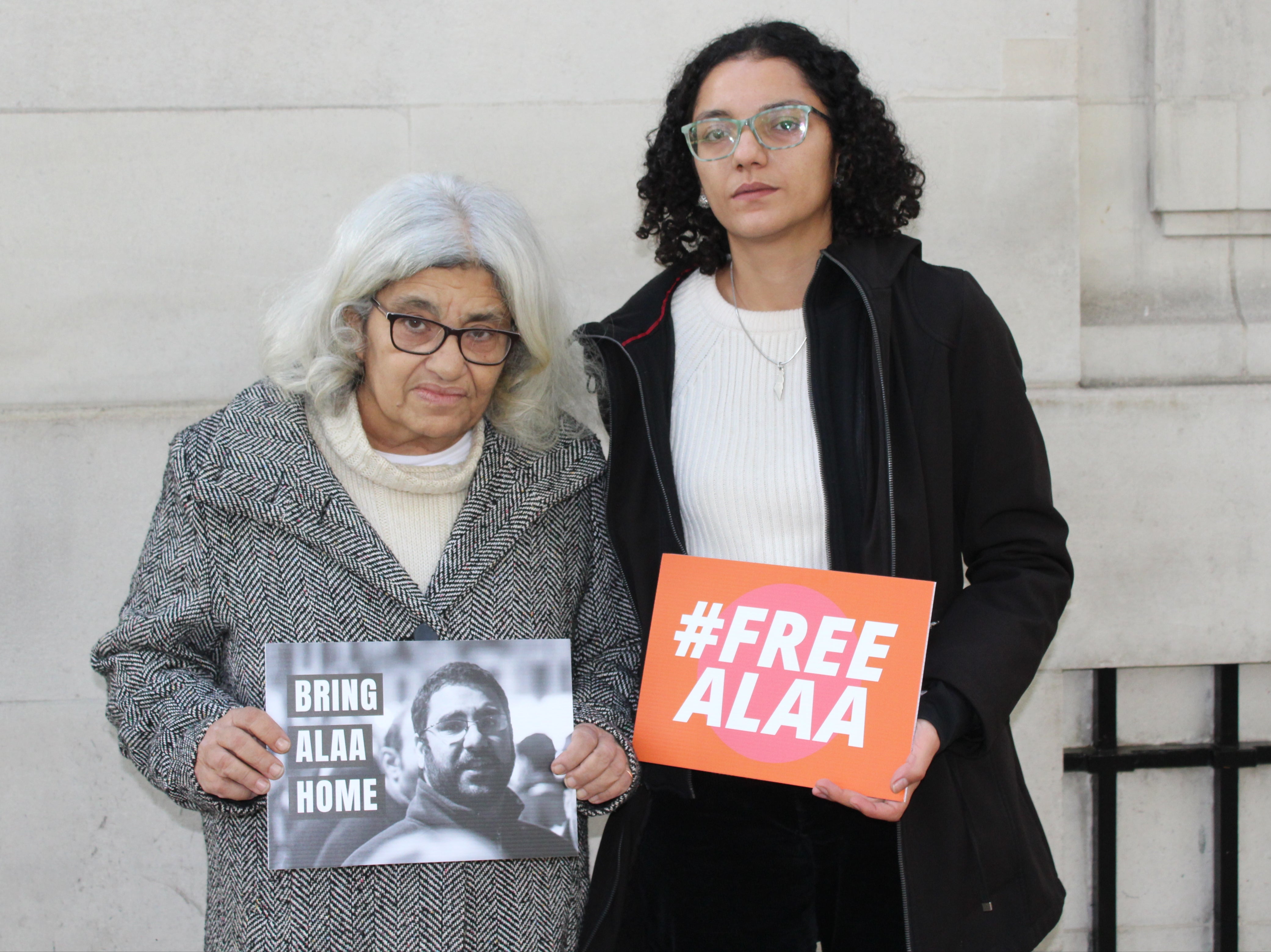 Laila Soueif, 68, stands next to her daughter Sanaa Seif in London holding signs calling for the release of Alaa Abdel Fattah