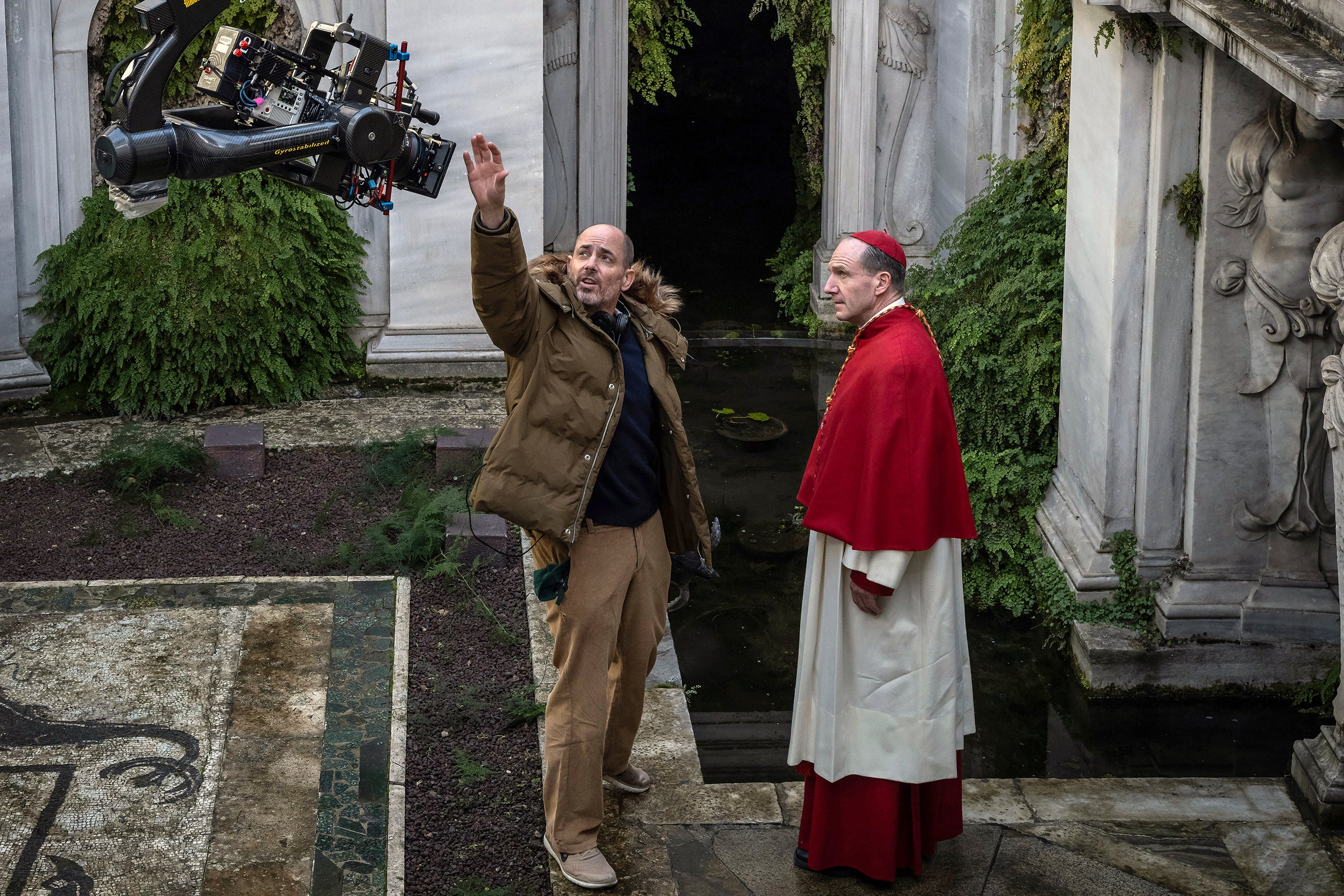 This image released by Focus features shows director Edward Berger, left, and actor Ralph Fiennes on the set of Conclave