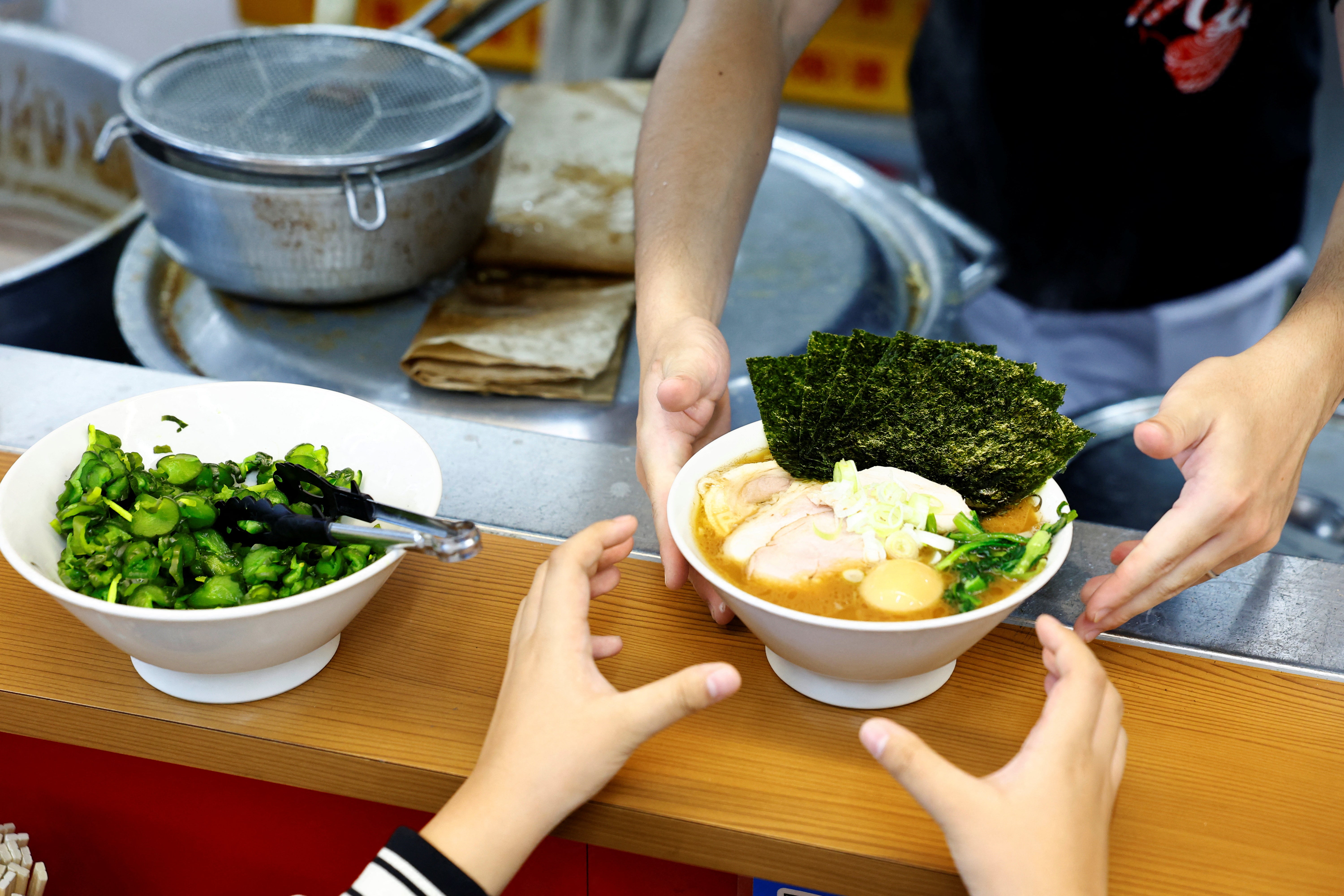 Um cliente recebe uma tigela de ramen na Menya Taisei, uma loja de ramen, em Tóquio, Japão, 22 de outubro de 2024