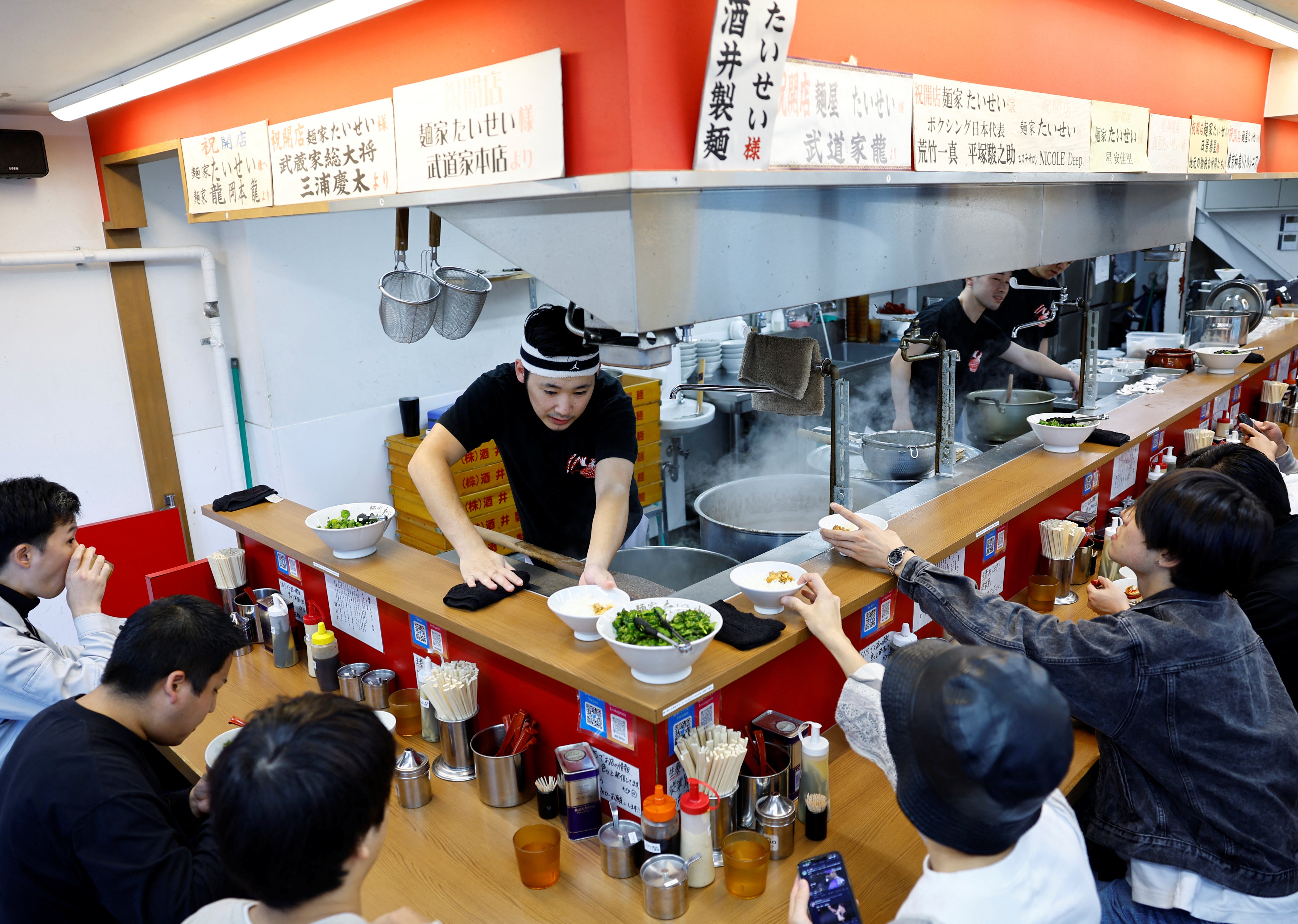 An employee serves to customers at Menya Taisei, a ramen shop, in Tokyo, Japan, October 22