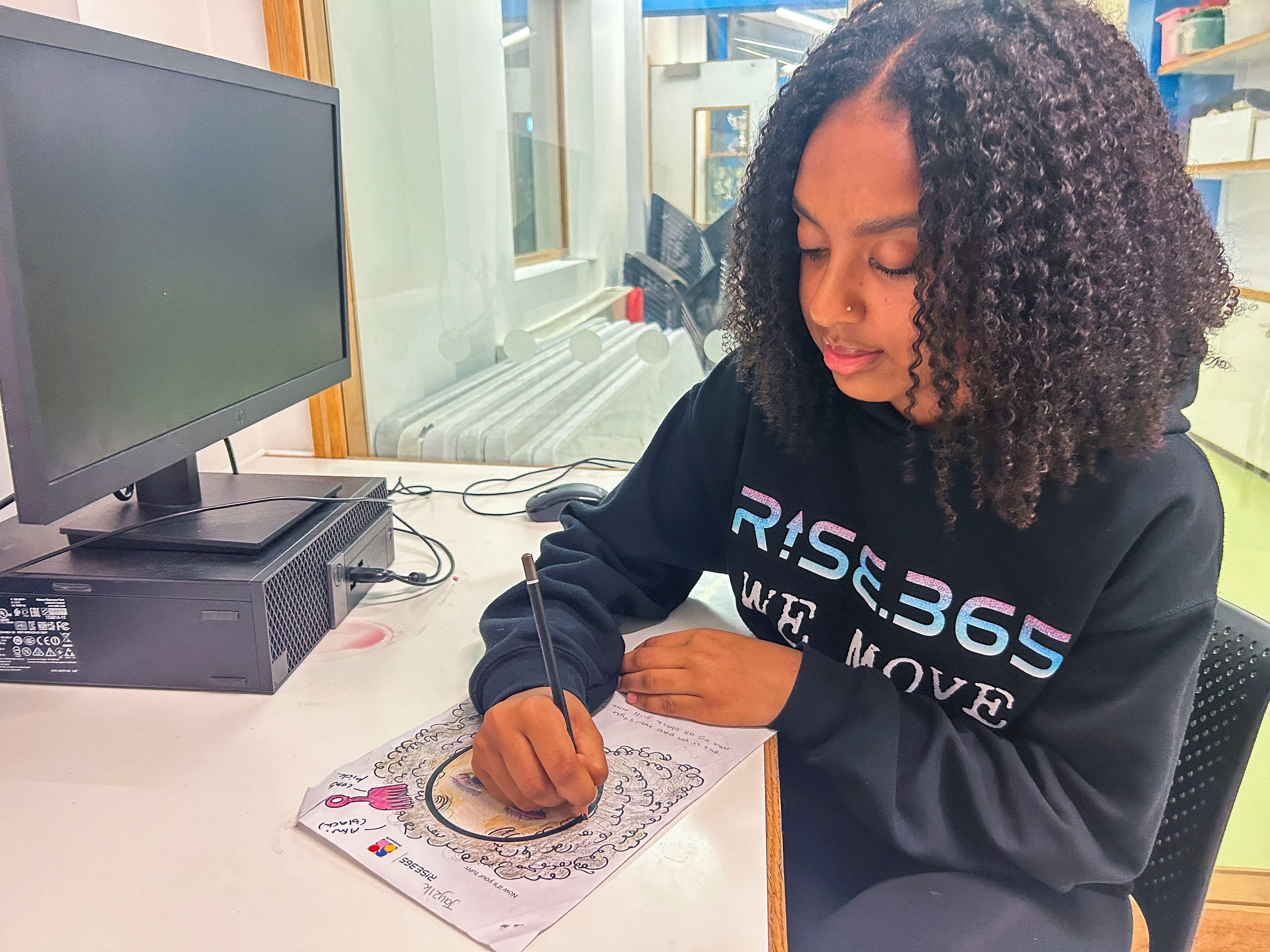 Student and Rise 365 young designer Jayzik Duckoo draws Afro hair emoji at the Concorde Youth Club in Hackney