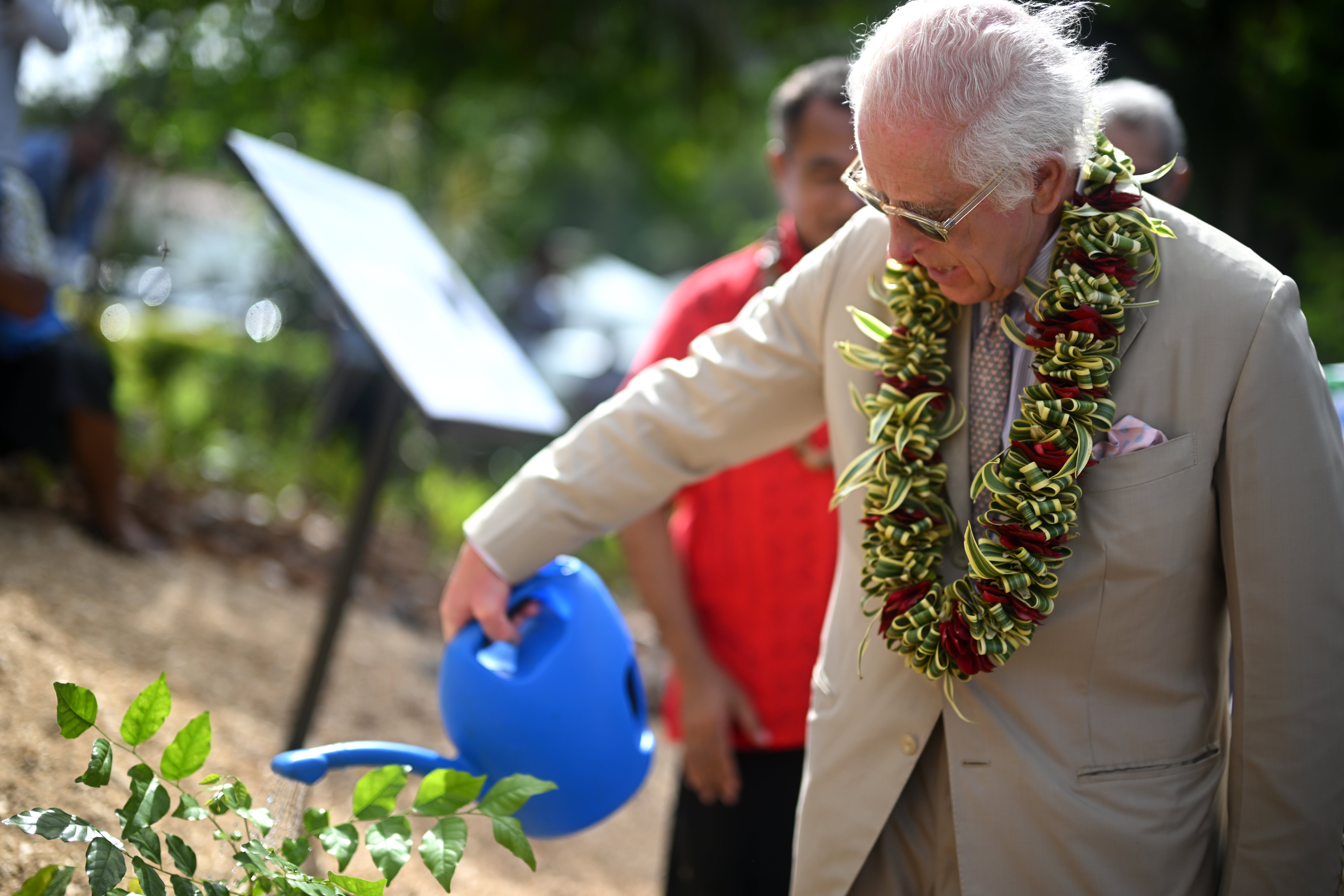 King Charles III waters a tree he planted after unveiling a plaque to officially open The King’s Garden