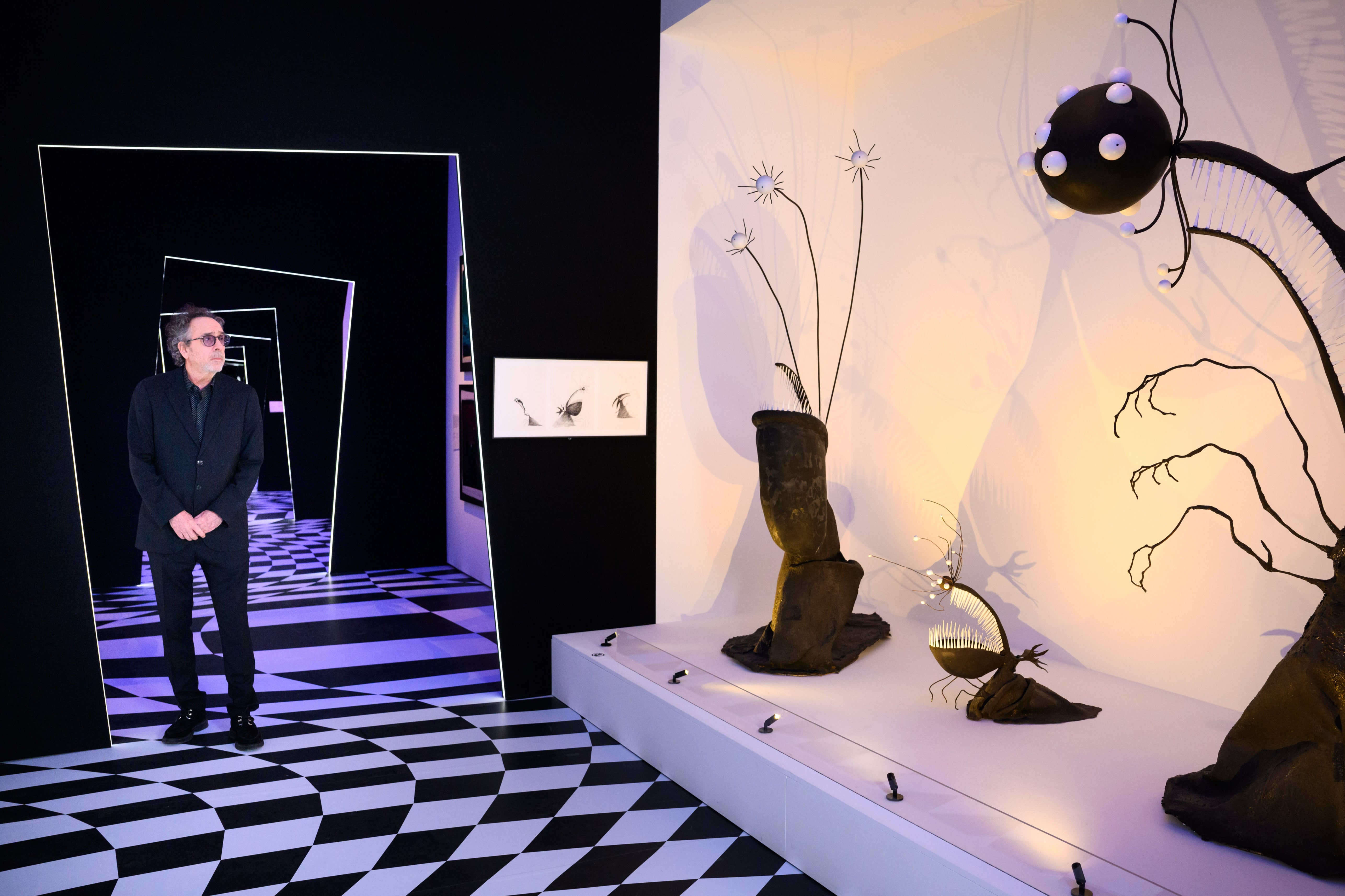 Tim Burton visits his London exhibition, which comes complete with an eye-popping floor design and askew doorways