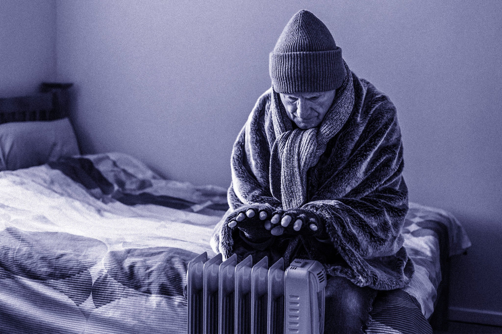 A retired senior man in his 70s sits at home inside his cold house in winter