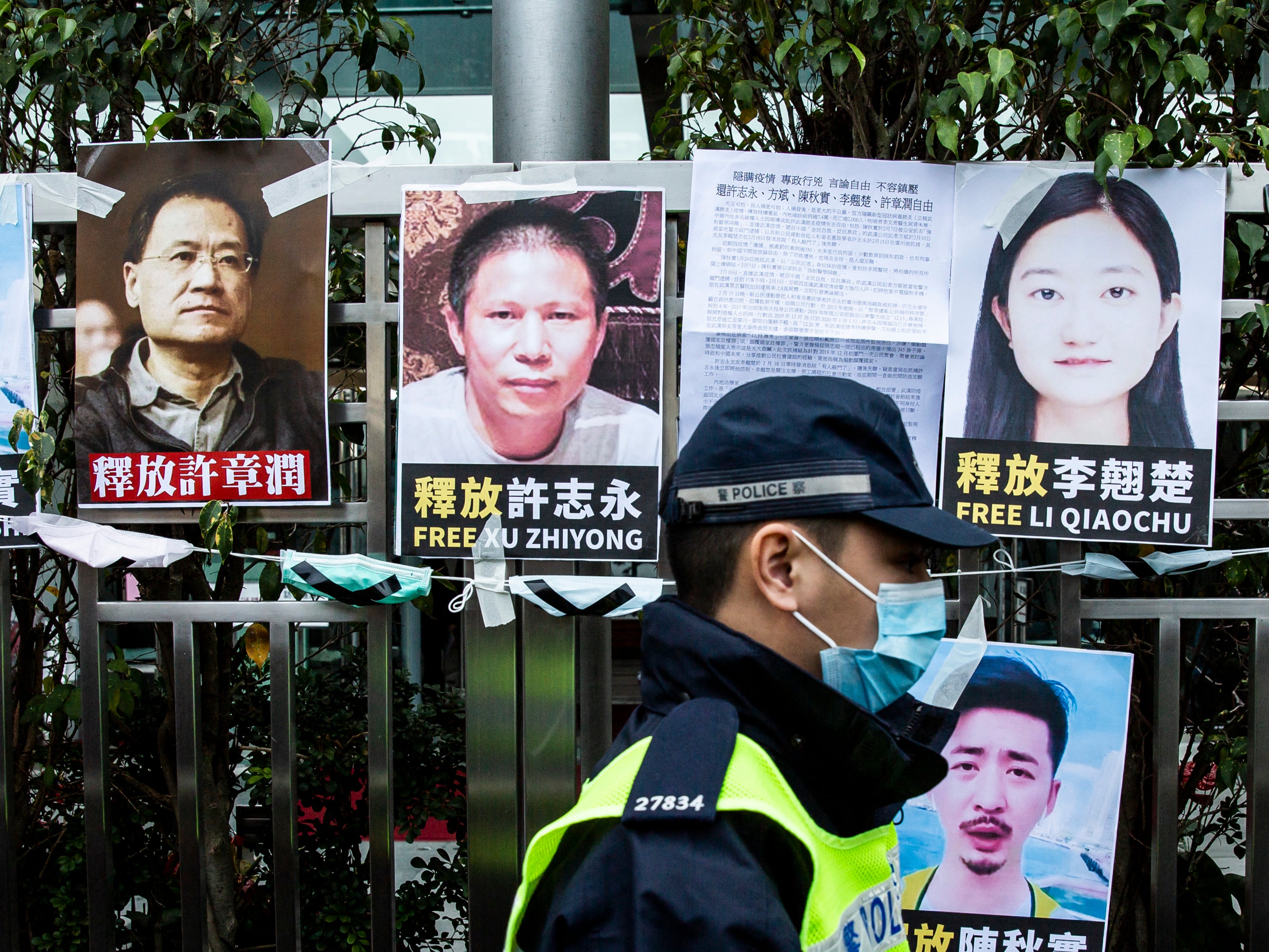 File. Police officer walks past posters of detained activists put up on a fence of the Chinese liaison office in Hong Kong