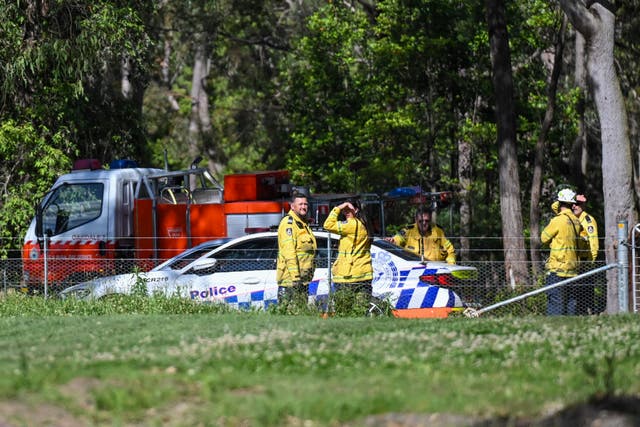 <p>Police and firefighters stand near the aircraft crash site southwest of Sydney, Australia, on 26 October 2024</p>