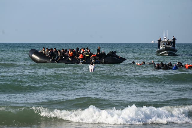 <p>Migrants swim to board a smugglers’ boat off a beach in northern France in order to attempt to cross the English Channel </p>