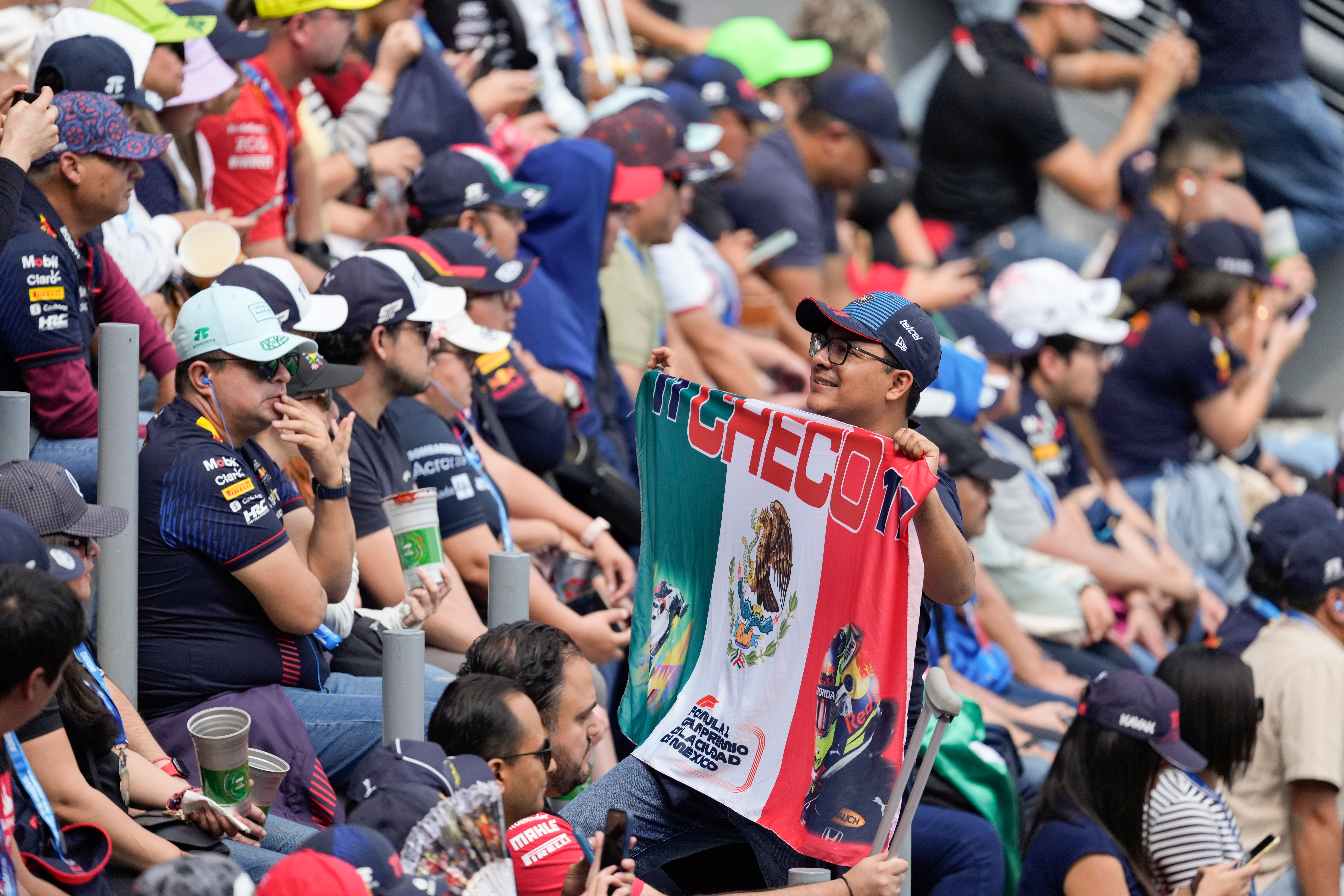 A fan of Red Bull driver Sergio Perez poses for photos with a Mexican flag during the third free practice