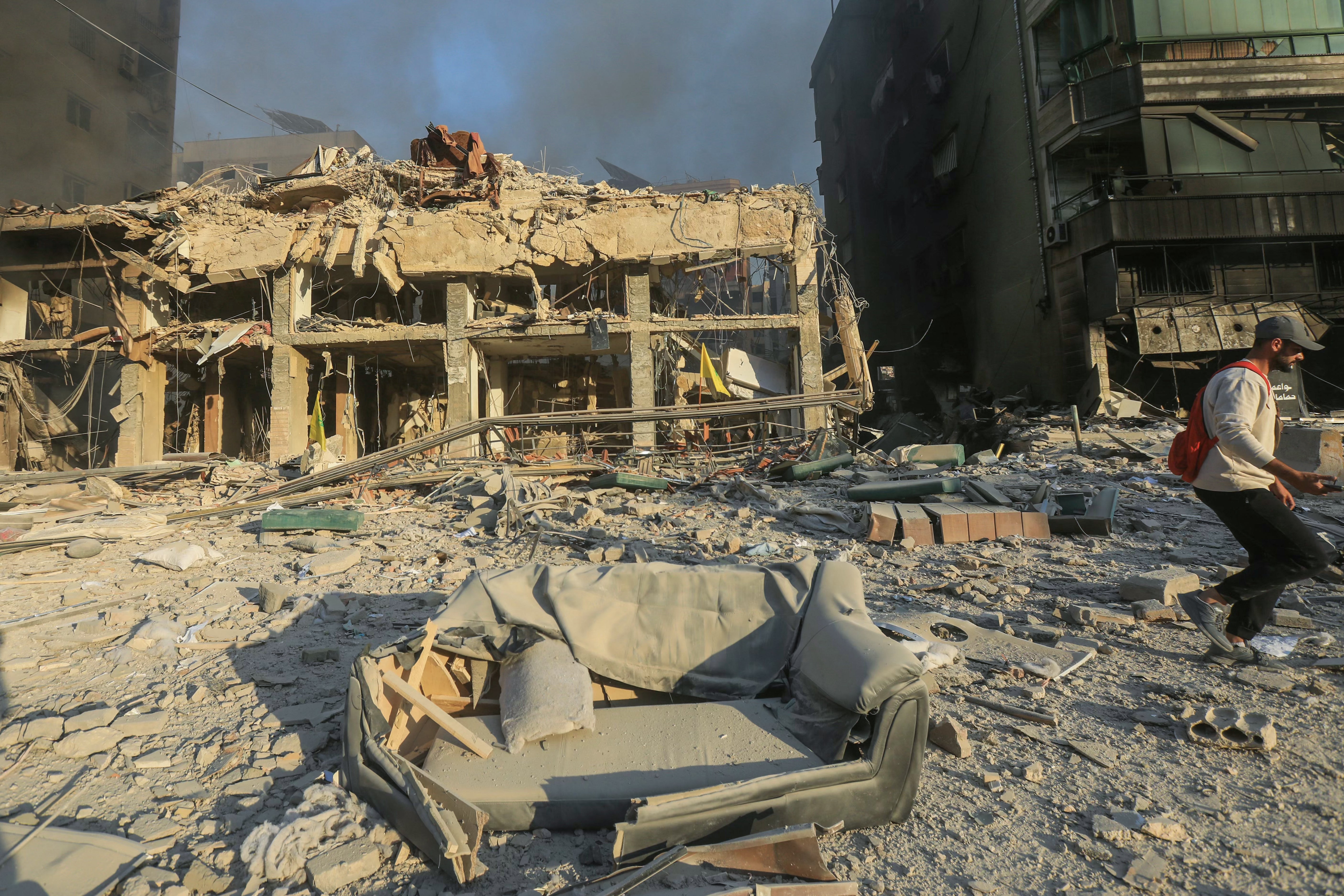 A man walks past destroyed and damaged buildings at the site of an overnight Israeli airstrike that targeted Beirut's southern suburbs