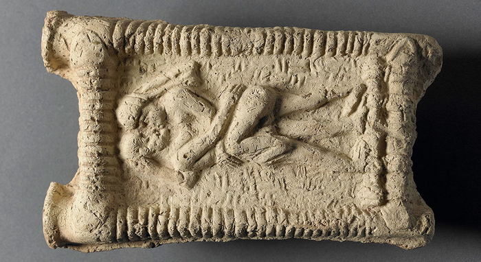 Babylonian clay model showing couple on couch engaged in sex and kissing