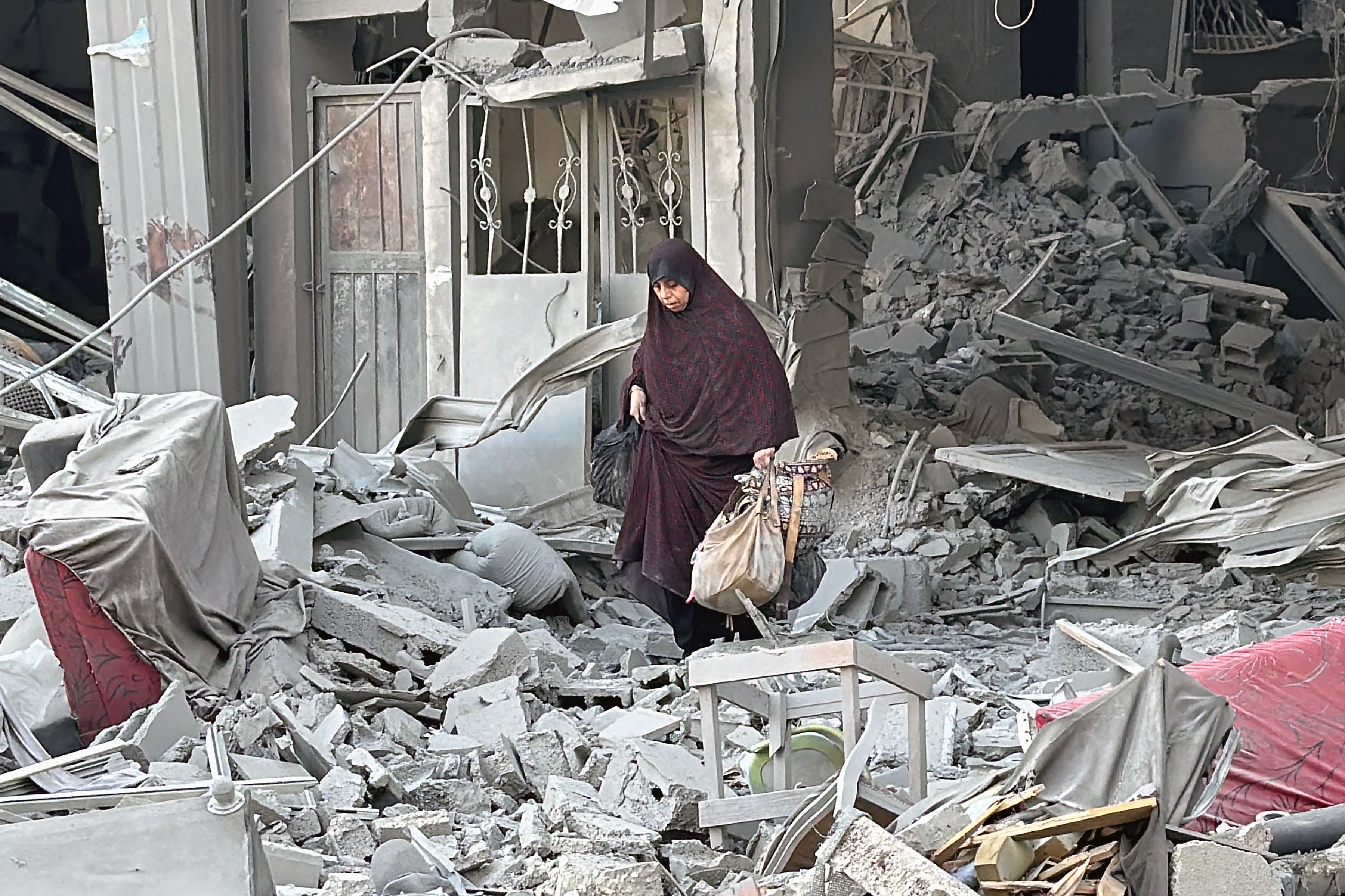 A woman walks through the rubble of a building following an Israeli strike in Beit Lahia in the northern Gaza Strip