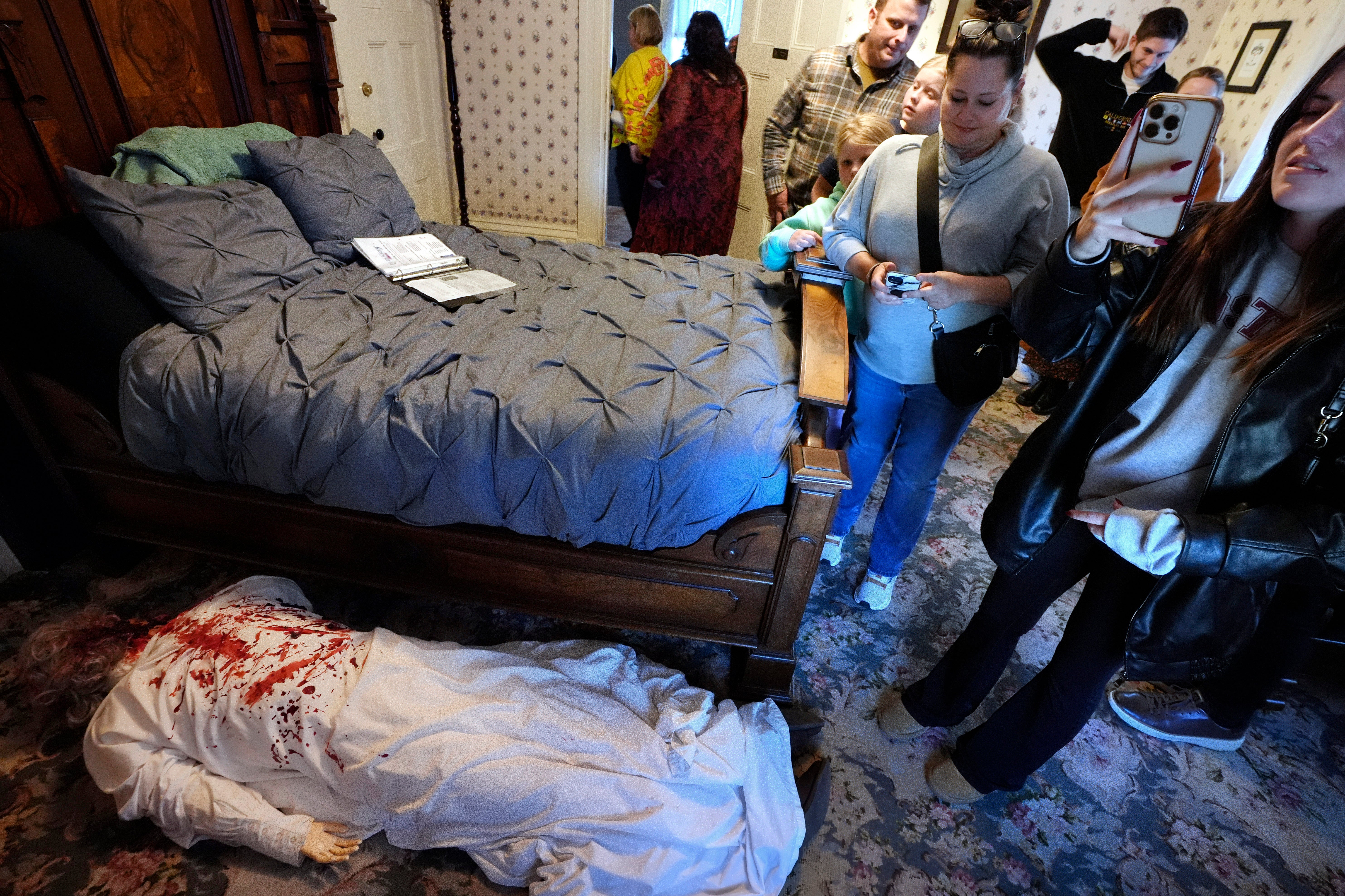 Visitors to the Lizzie Borden House view a mannequin in costume, below left, meant to portray a likeness of the murder scene of Abby Borden, while visiting the site of an 1892 double axe murder