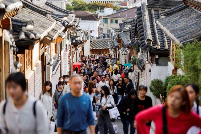 <p>A large crowd of tourists walks through Bukchon Hanok Village in Seoul</p>