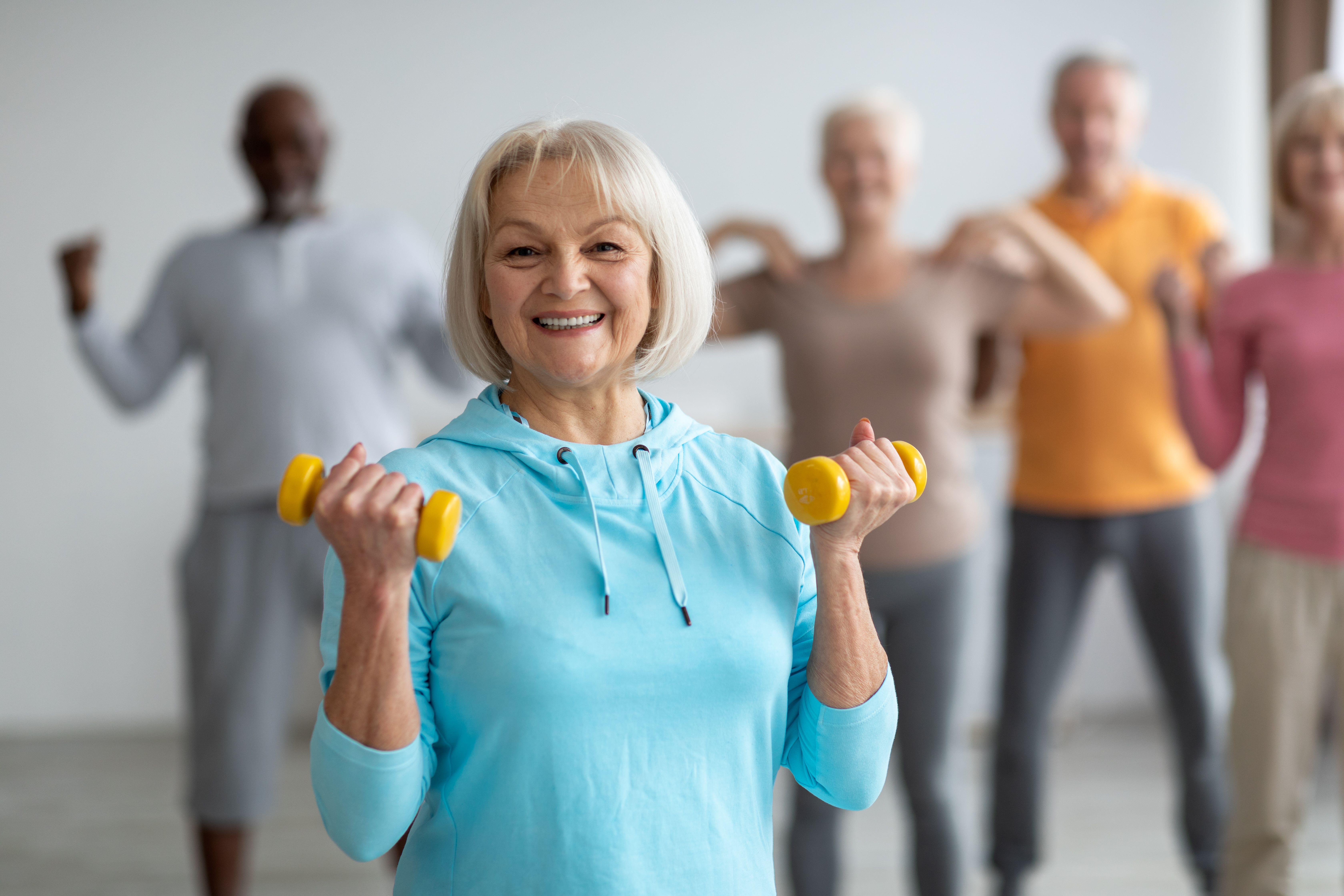 A senior woman taking part in a weight training class