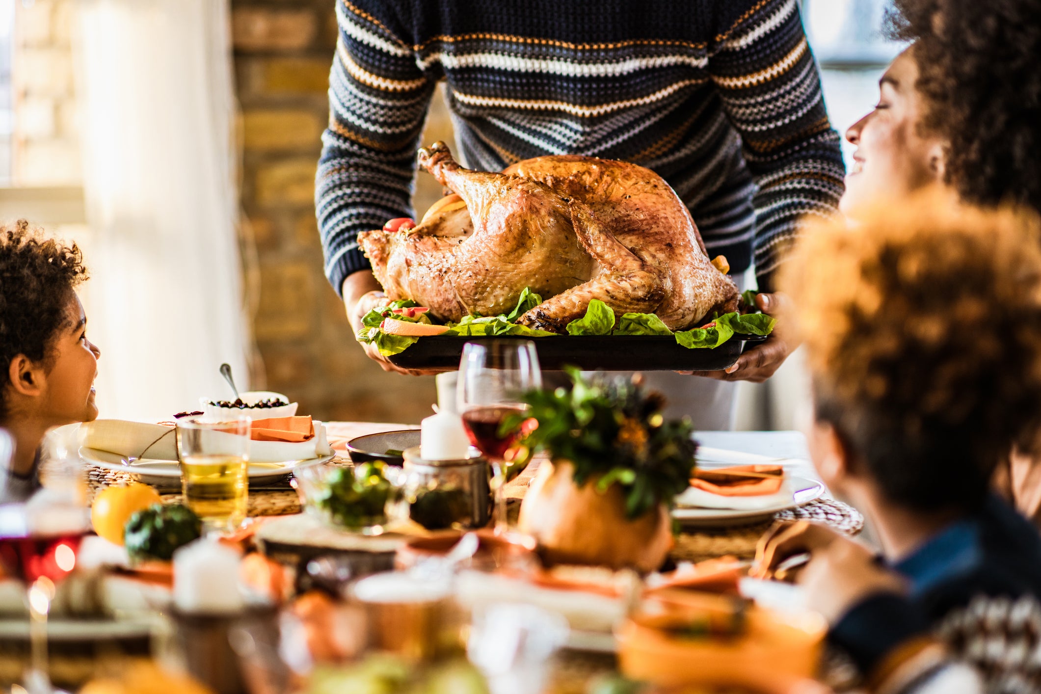 An uncarved turkey being served at a Thanksgiving table