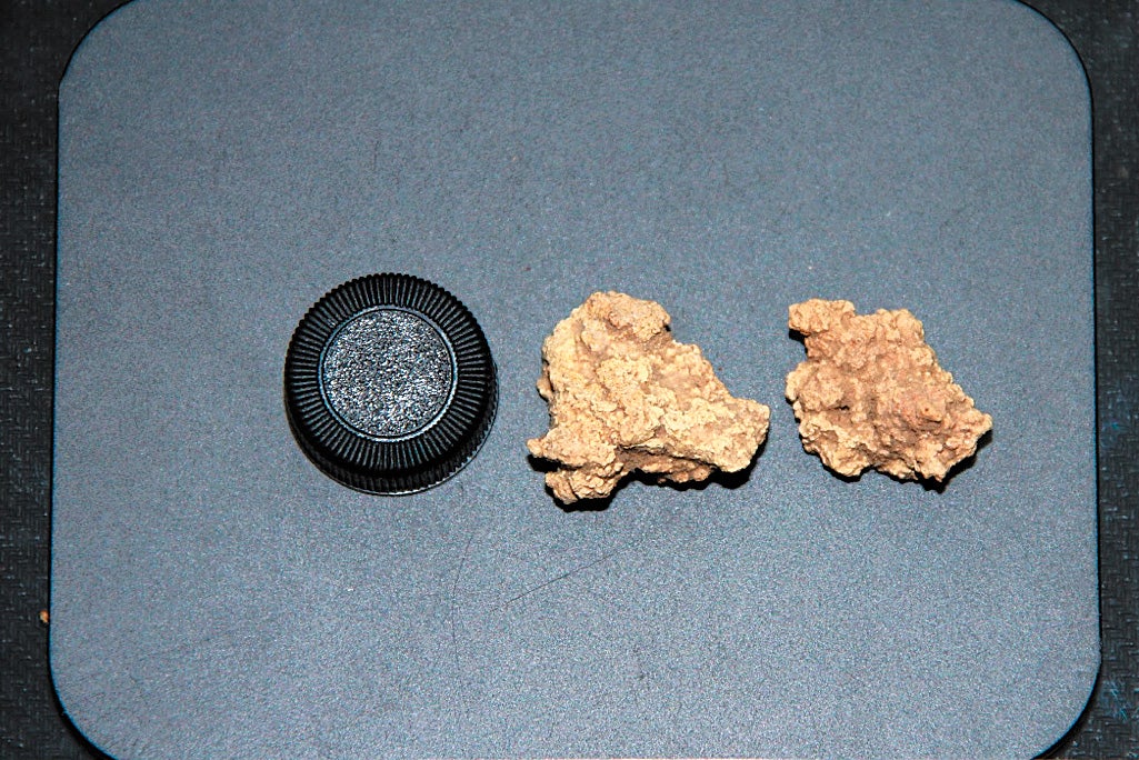 An undated photo compares the size of a glass tube cap and two Bronze Age kefir cheese samples unearthed from a tomb site in the Xinjiang Uygur autonomous region