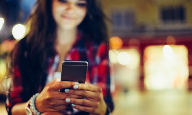 <p>A teenage girl uses her cell phone. Social media use, emails and texts all have a quantifiable carbon footprint that may surprise some users</p>