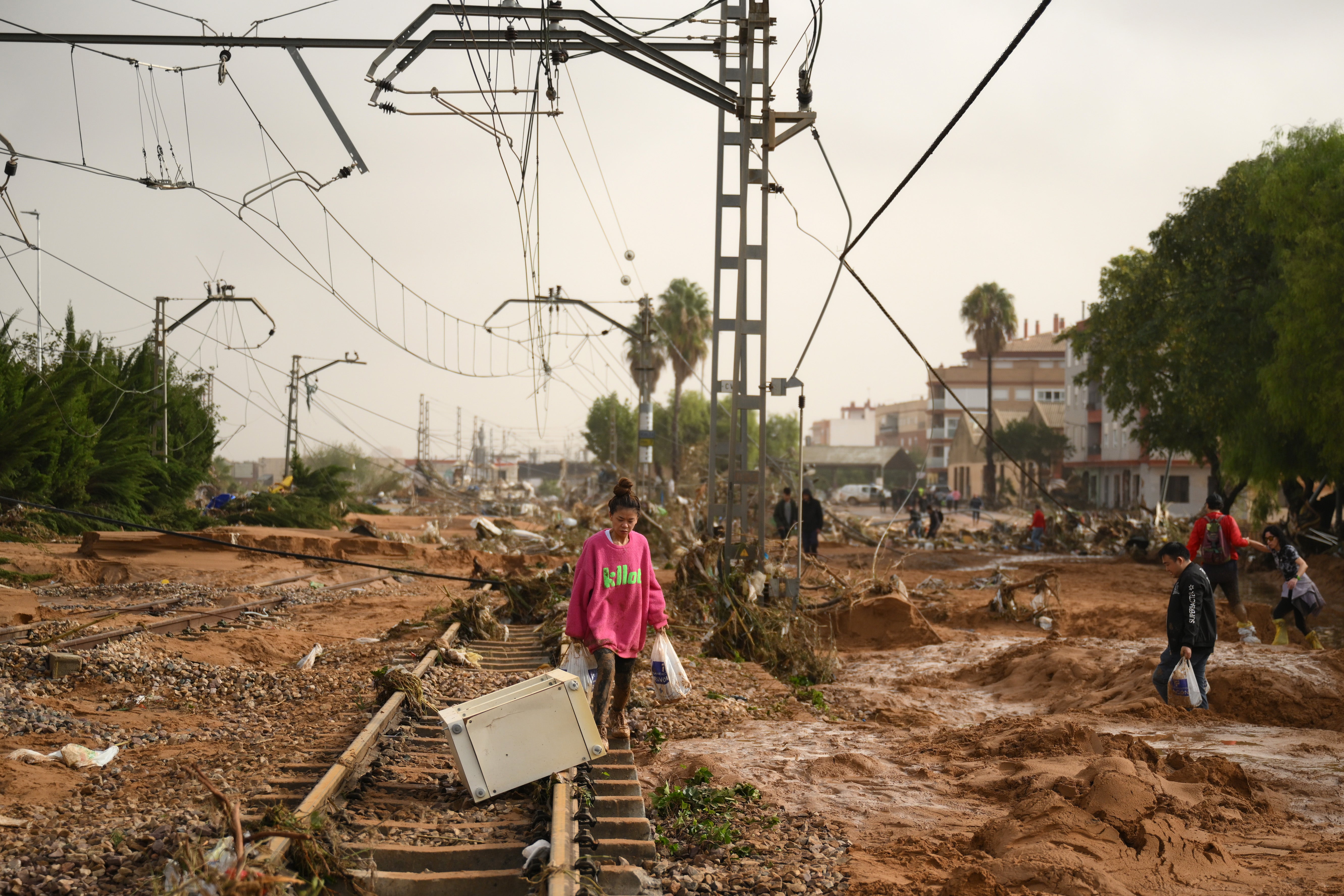 A woman walks along train tracks covered debris after flash-flooding hit the region