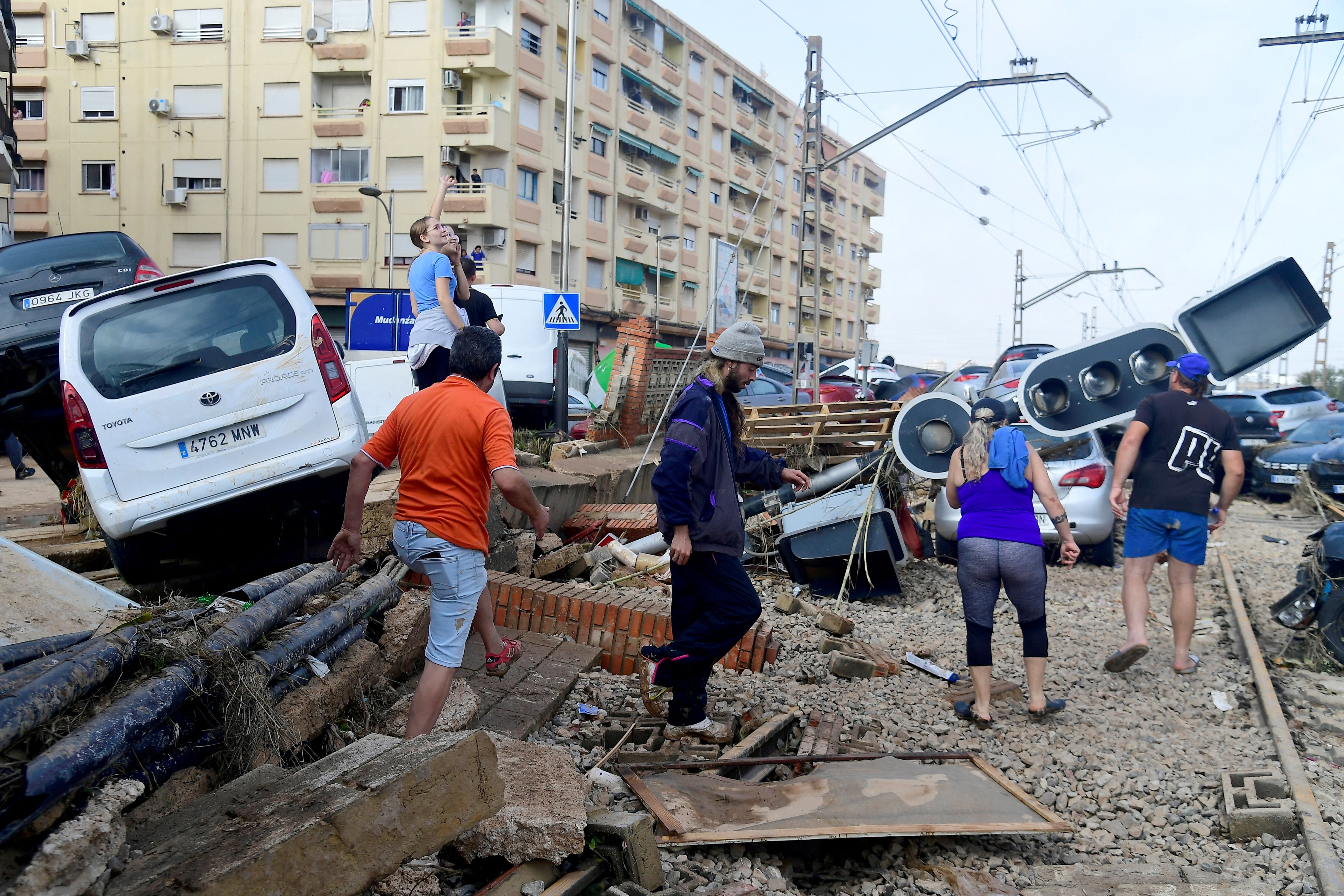 Residents walk next to piled up cars on railway tracks following deadly floods in Sedavi, south of Valencia