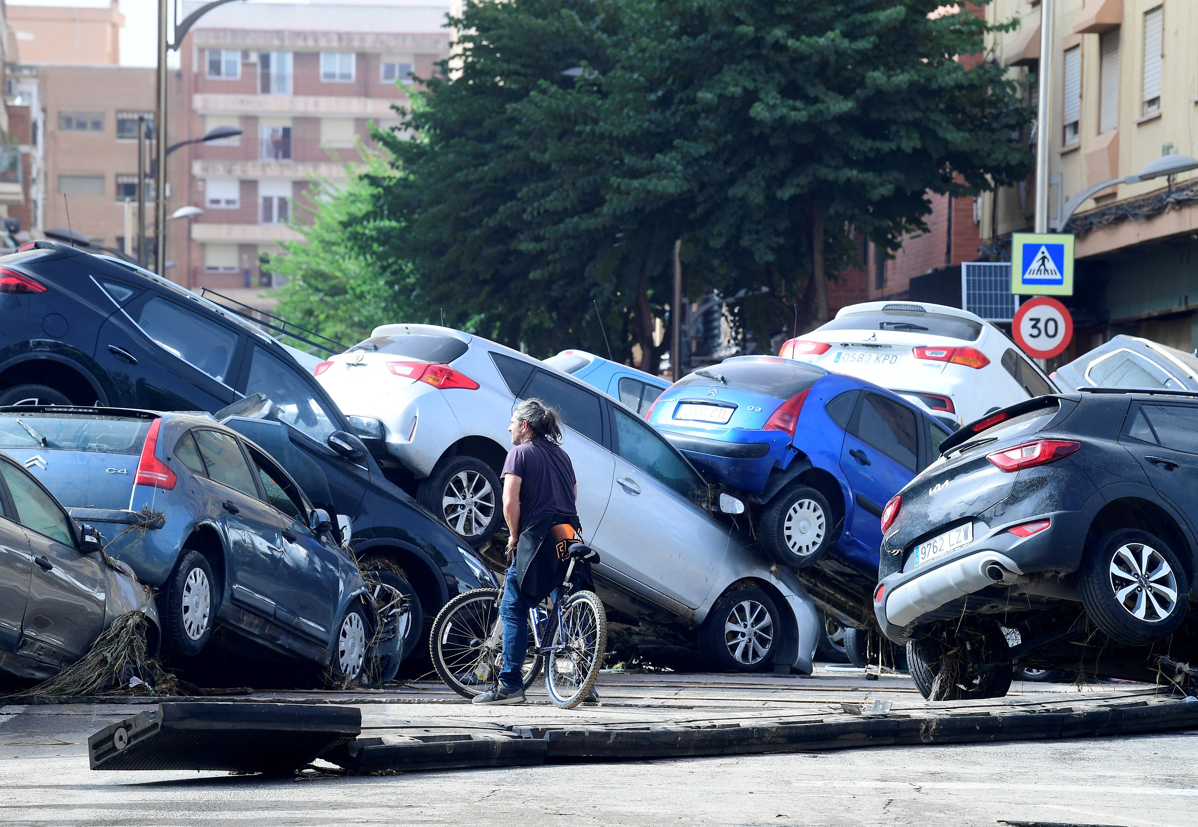 A cyclist stands next to piled up cars following deadly floods in Sedavi, south of Valencia