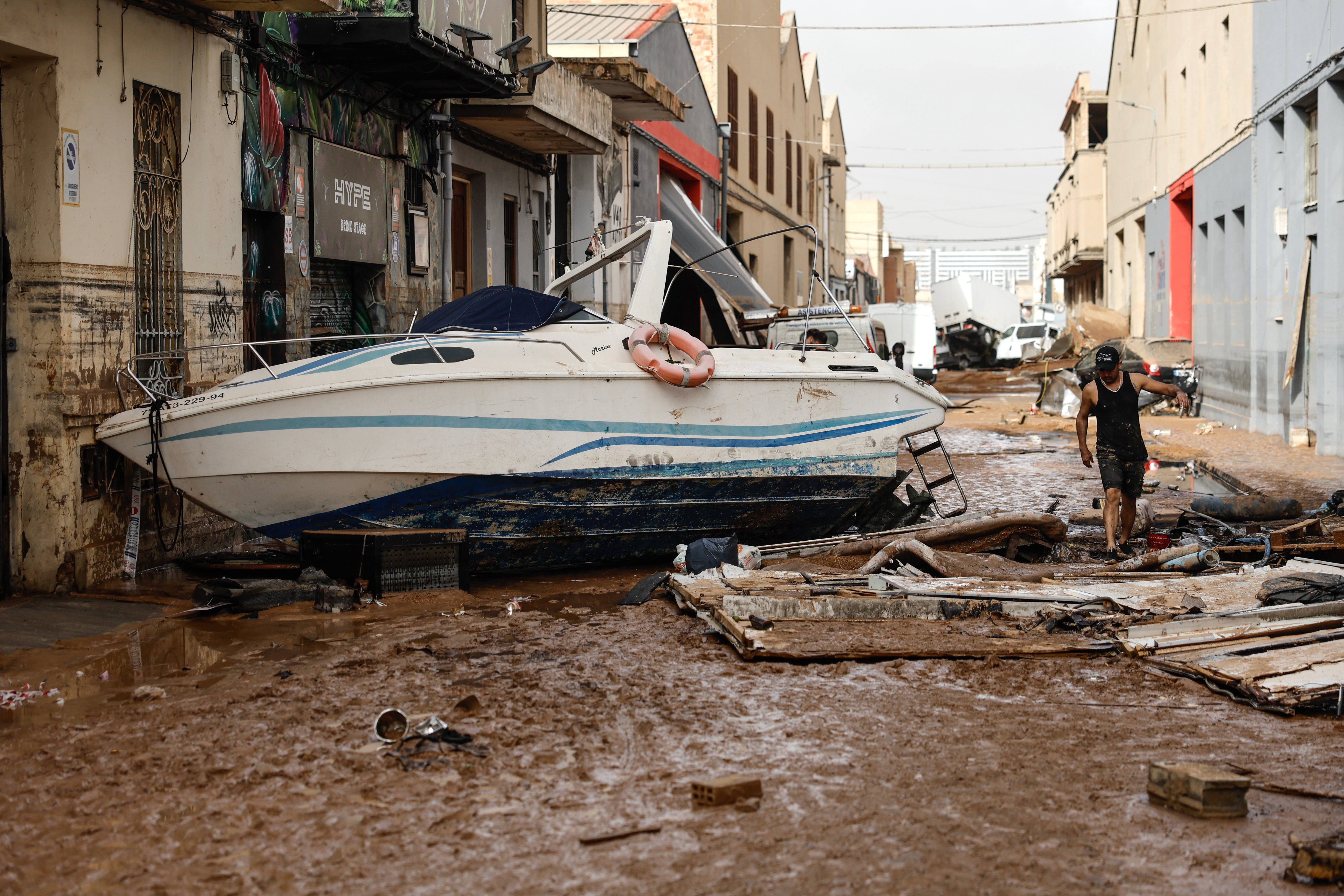 A person walks past a damaged boat in the flood-hit municipality of Sedavi, in the province of Valencia, eastern Spain