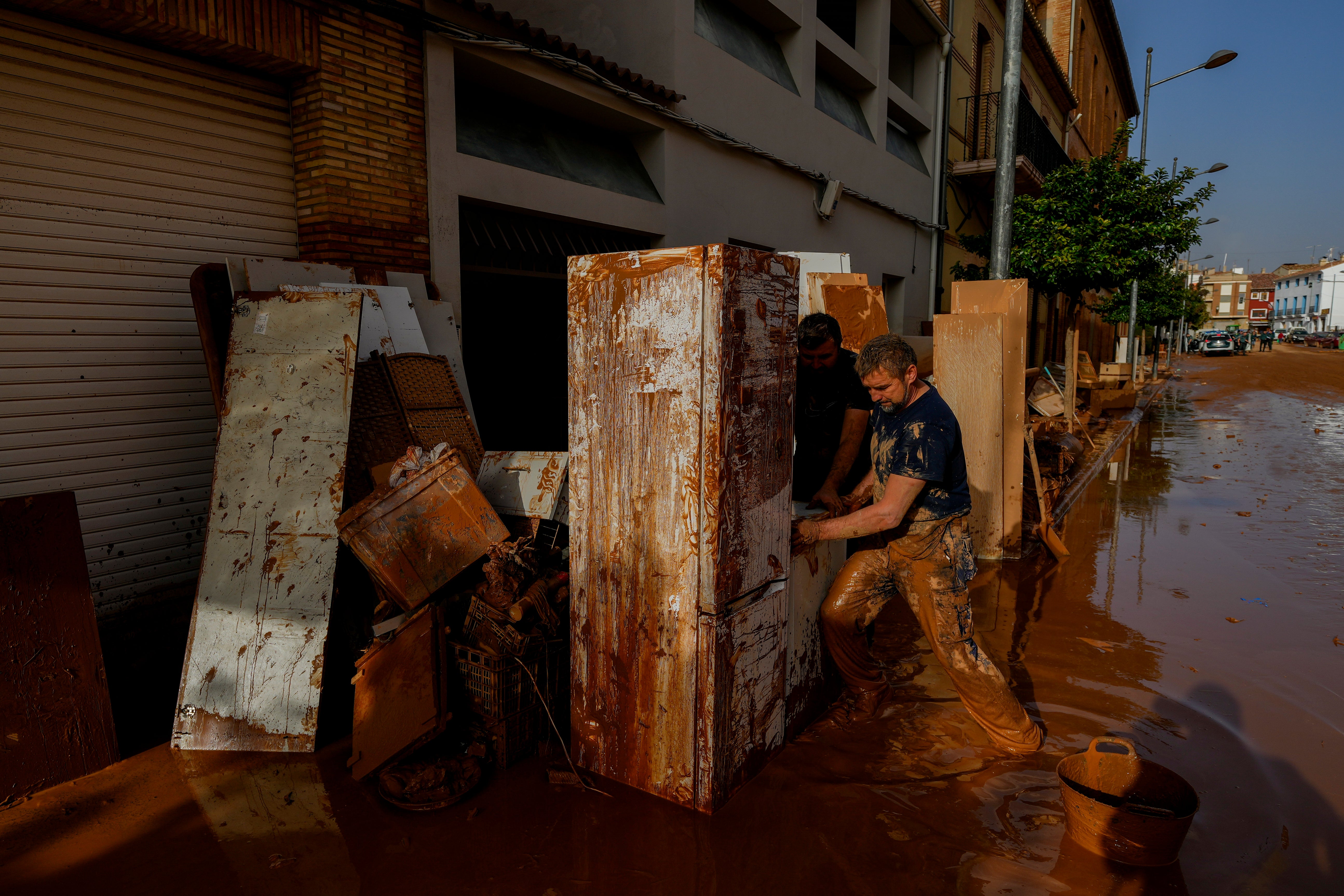 A man tries to move white goods covered in muddy water in Utiel