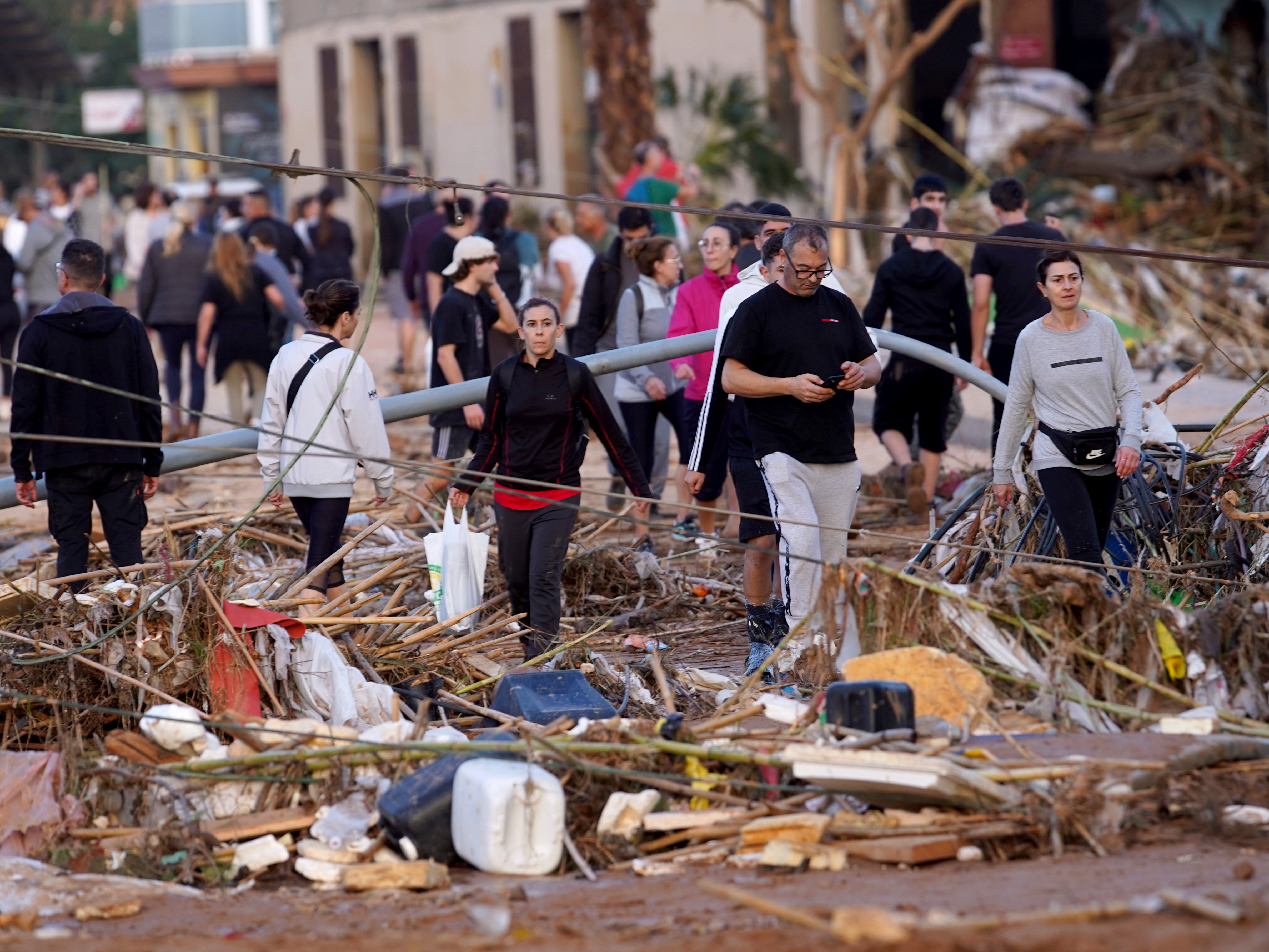 Residents walk in a street after flooding in Paiporta, near Valencia