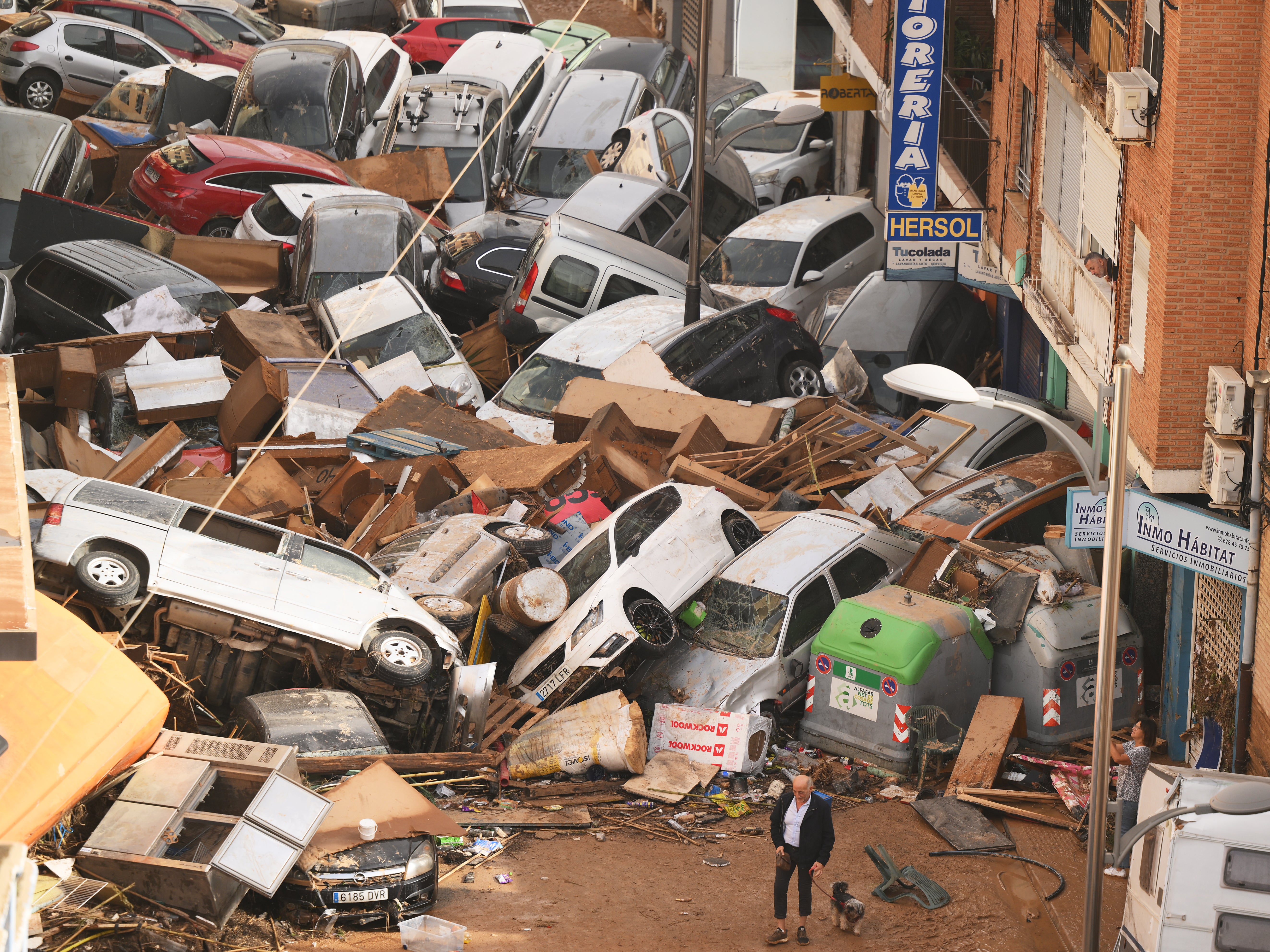 Cars piled high on the street block the man and his dog