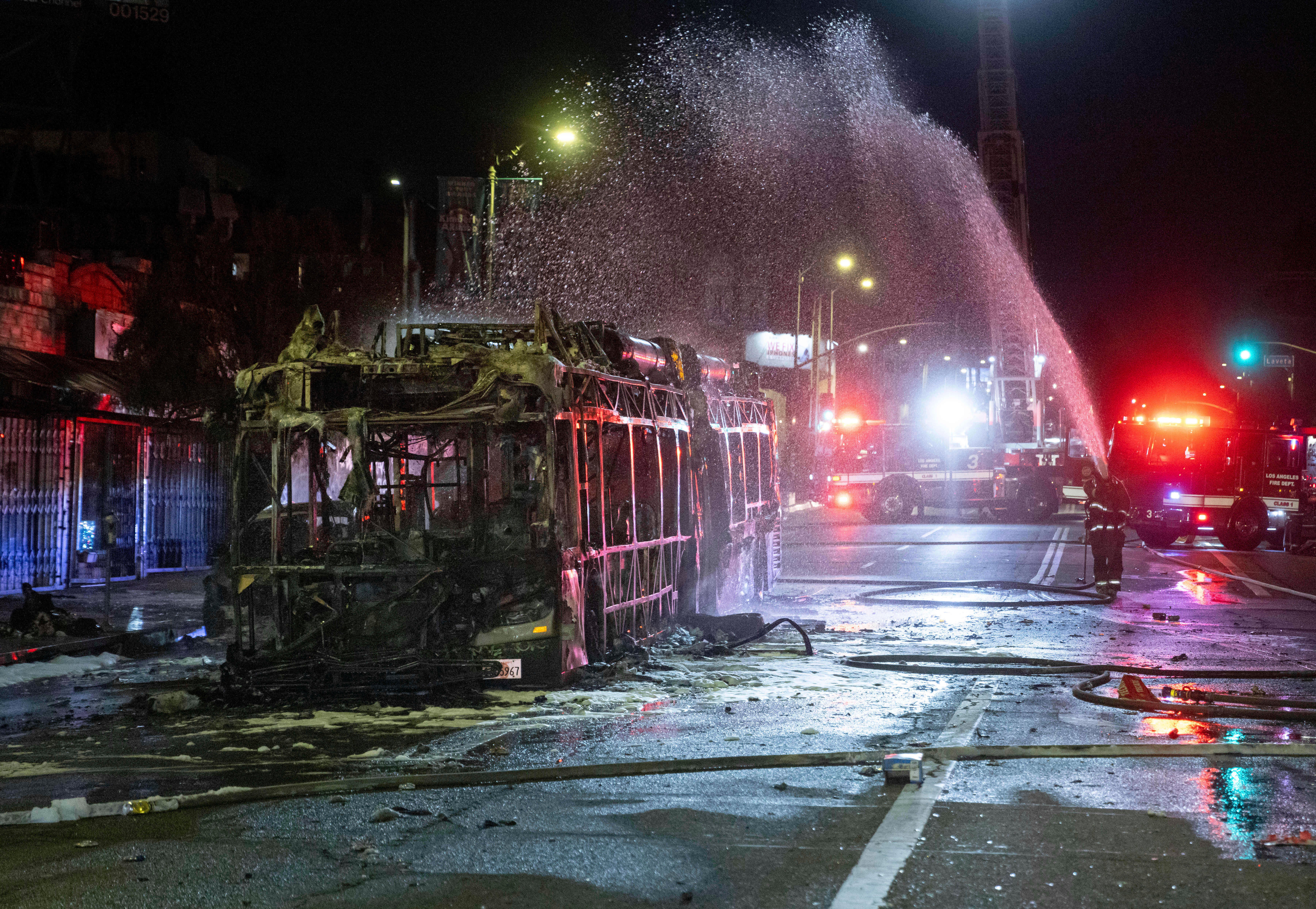 Firefighters douse water on a bus that was set on fire at Sunset and Echo Park after people gathered on the streets after the Los Angeles Dodgers defeated the New York Yankees to win the baseball World Series