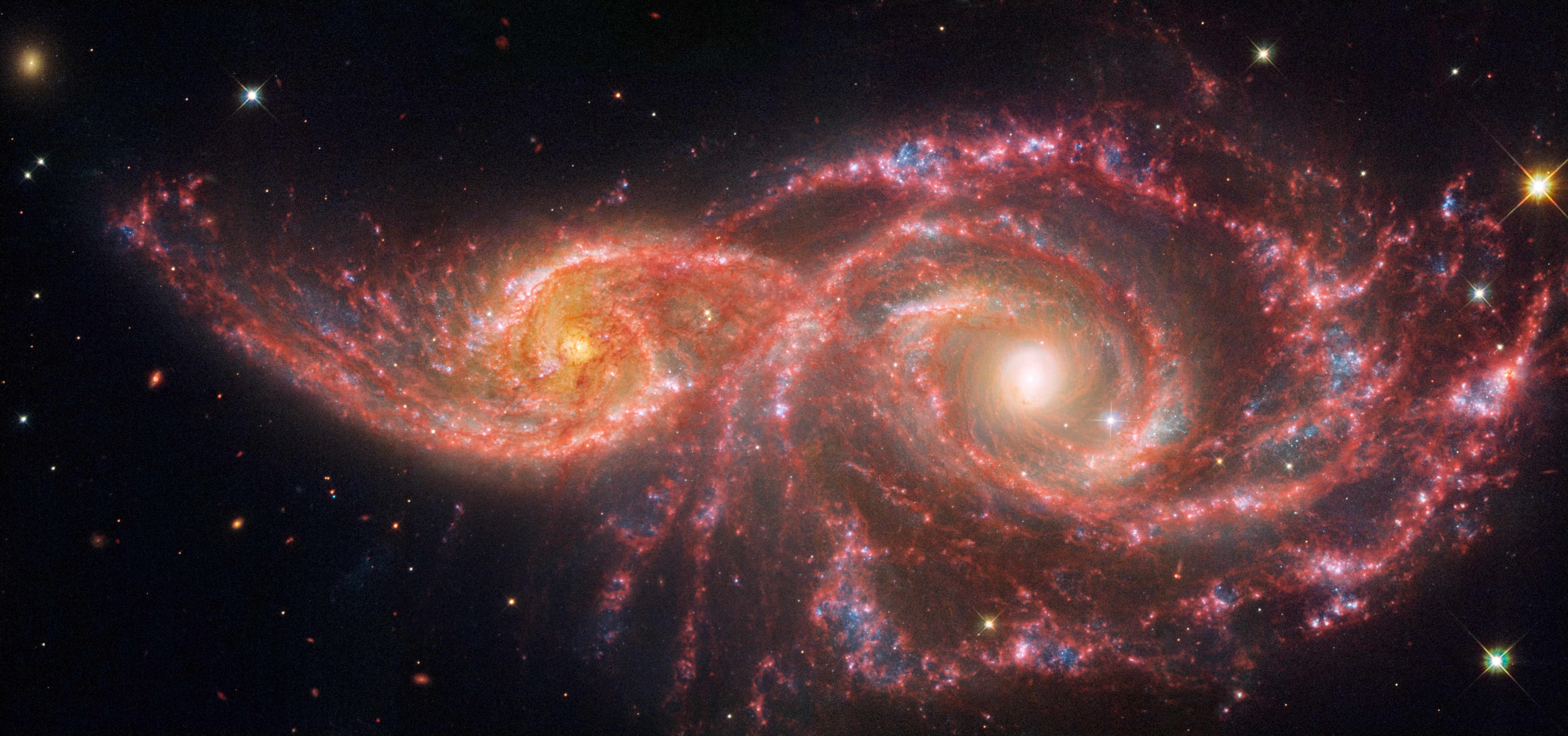 NASA’s James Webb Space Telescope and Hubble Space Telescope captured a pair of spiral galaxies some 114 million light-years from Earth. The smaller galaxy on the left, known as IC 2163, passed behind NGC 2207 millions of years ago.