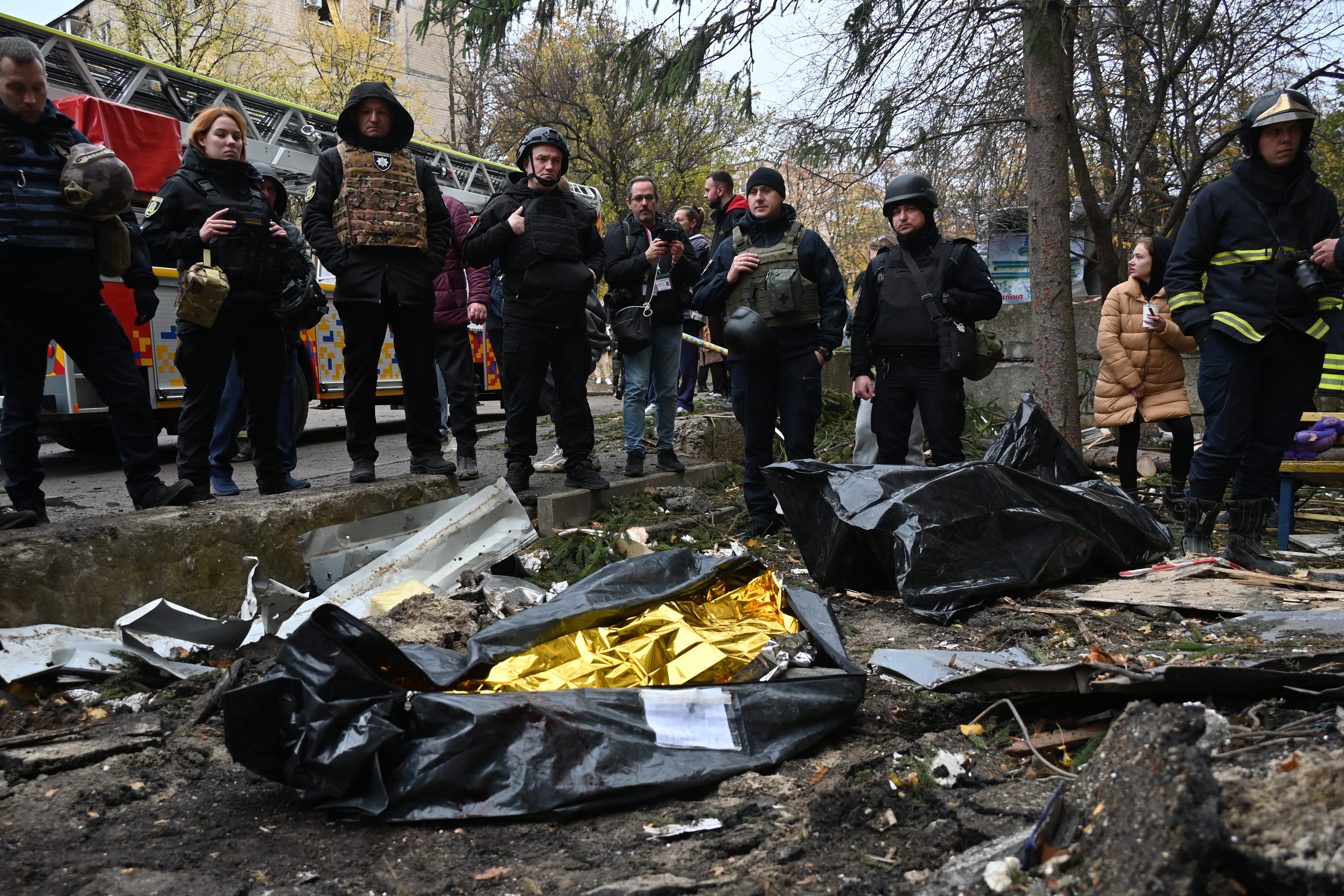 Ukrainian law enforcement officers stand next to the bodies of killed people in plastic bags following a missile attack in Kharkiv