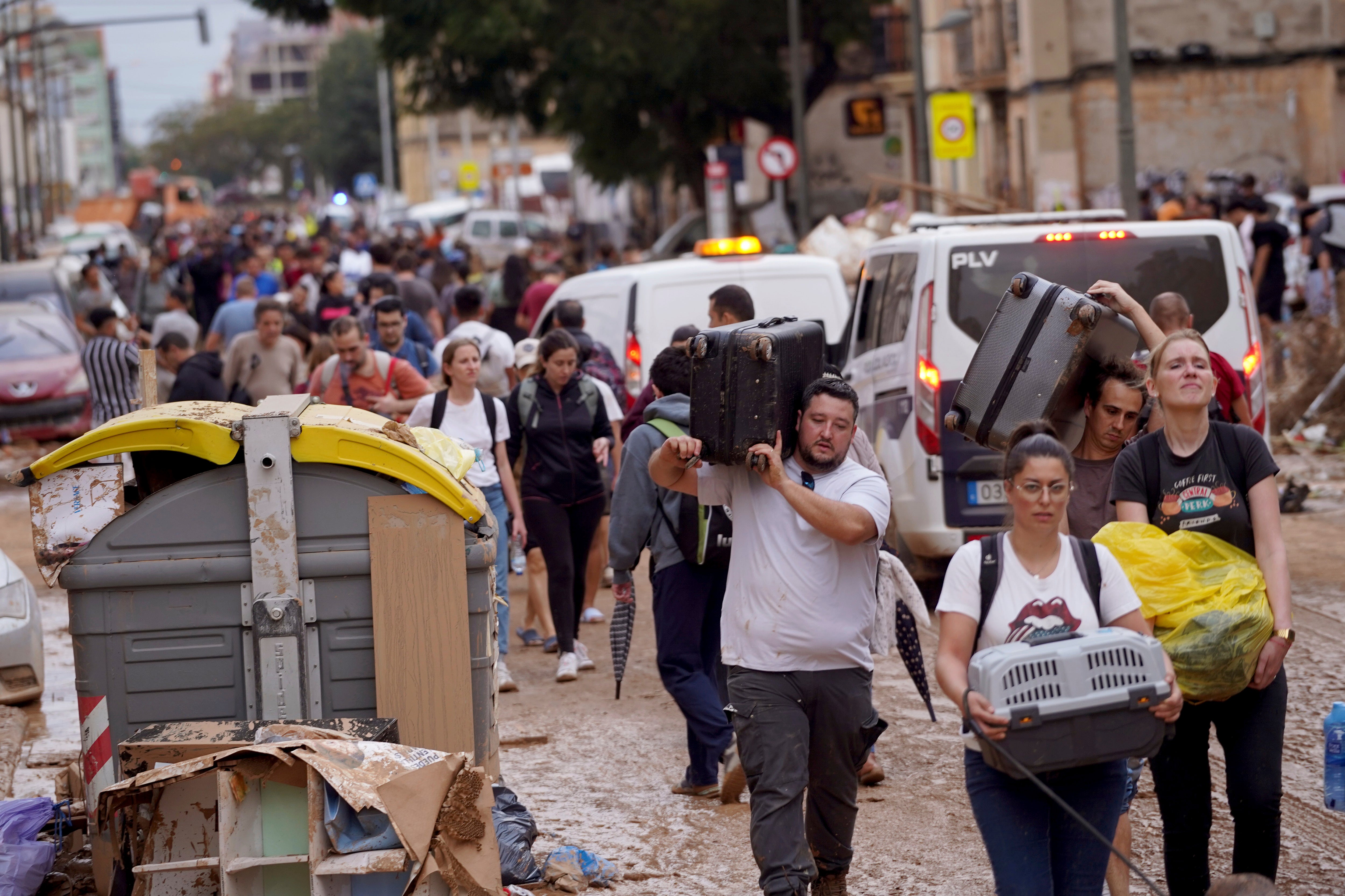 Residents carry their belongings as they leave their houses affected by floods in Valencia, Spain