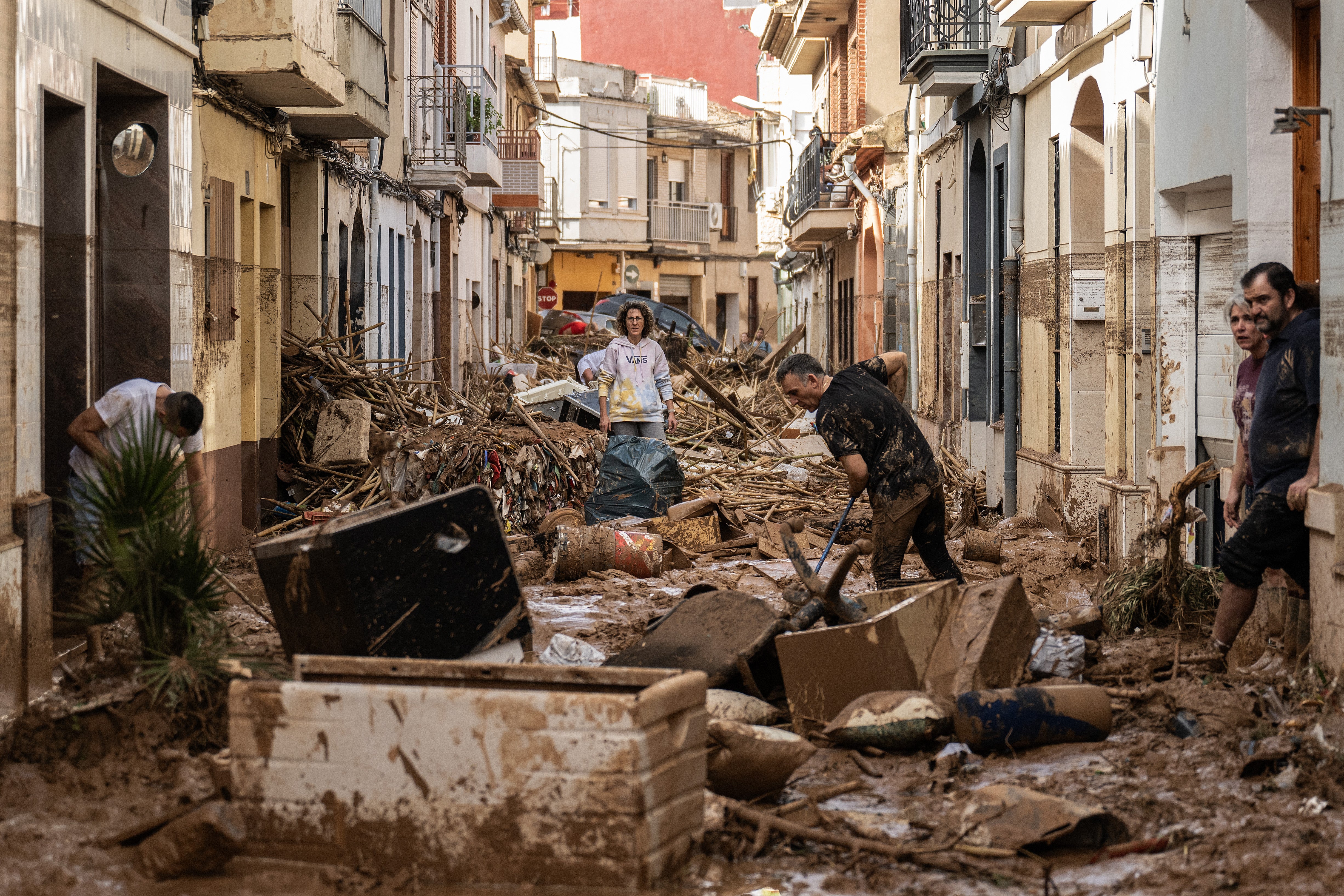 Residents clean up a mud-and-debris-covered street after flooding hit Paiporta, Valencia