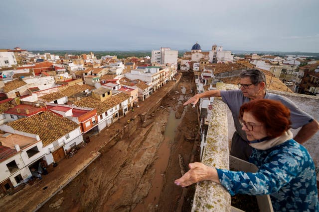 <p>Two people look out over an area affected by floods in Chiva, Spain</p>