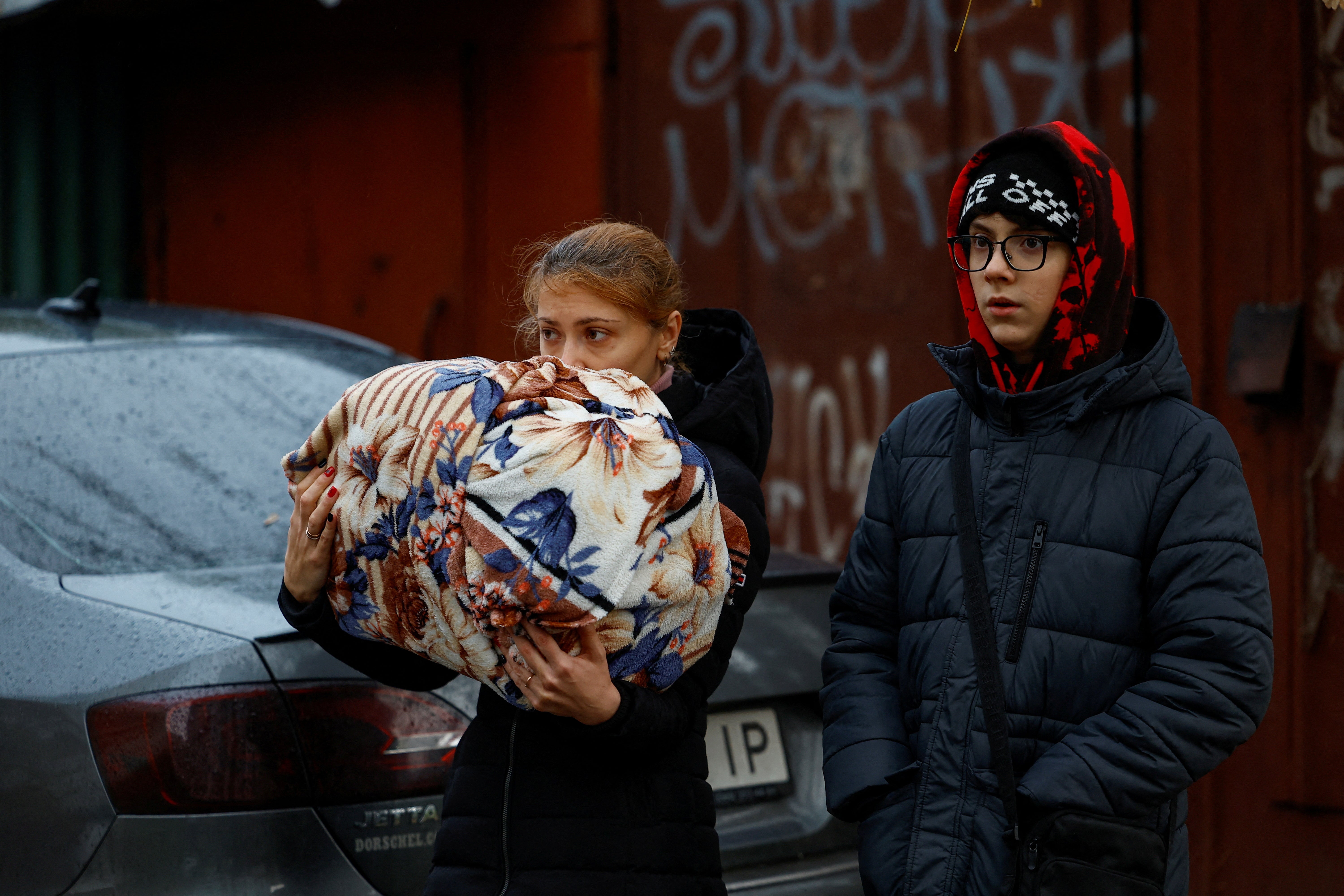 A resident clings onto a cat wrapped up in a bundle following the Kyiv strikes