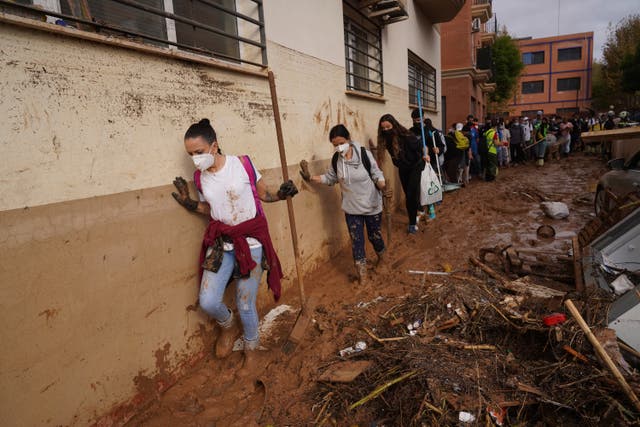 <p>Volunteers walking through thick mud after heavy rainfall flooded areas in Valencia  </p>