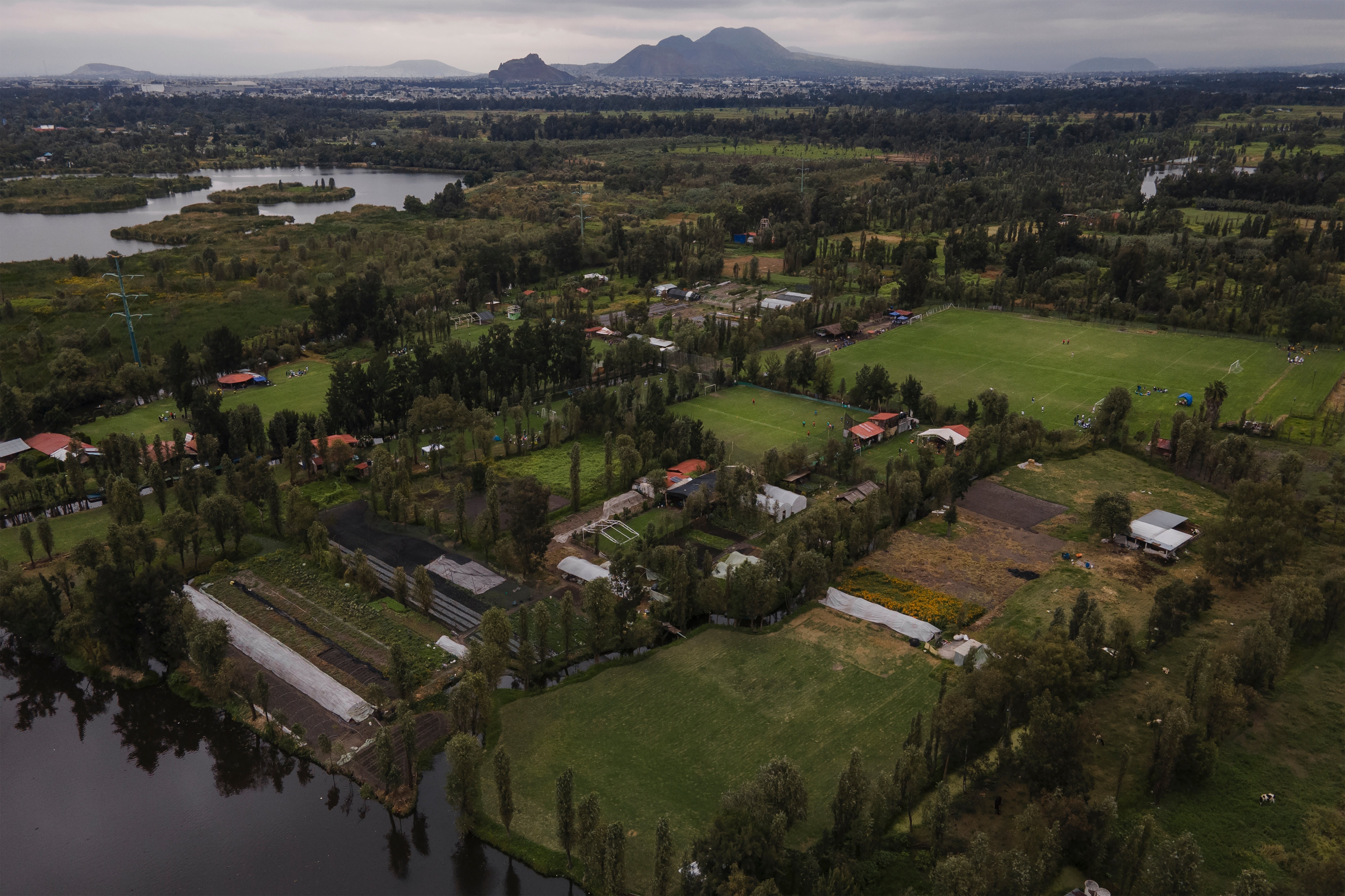 Small ancestral floating gardens are visible next to new soccer fields on the Xochimilco Lake