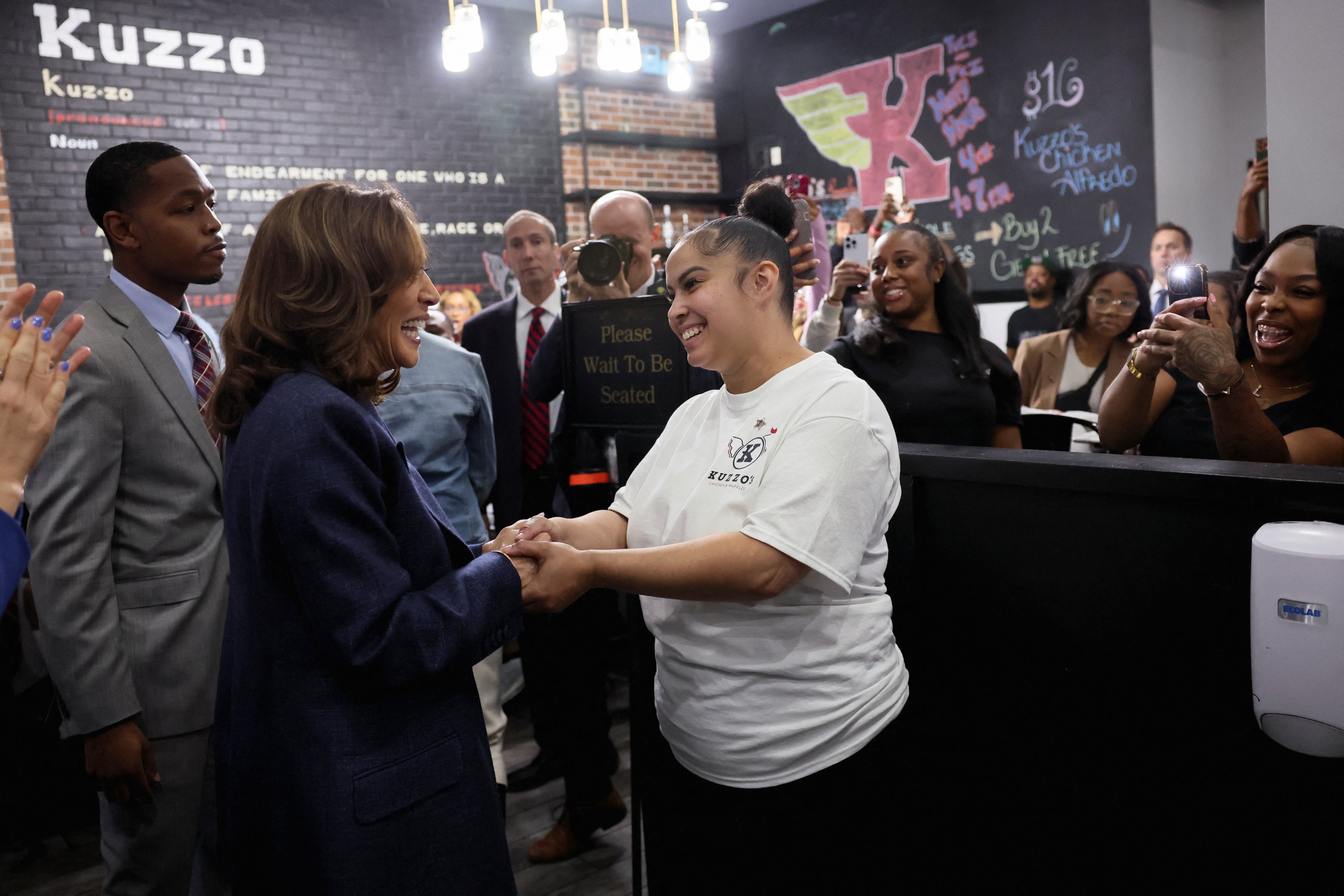 Kamala Harris greets a woman at Kuzzo’s Chicken & Waffles, in Detroit