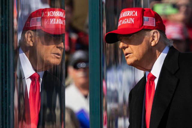 <p>Former US President Republican presidential candidate Donald Trump stands behind bulletproof glass as he arrives to speak during a campaign rally in Lititz, Pennsylvania, on November 3, 2024</p>