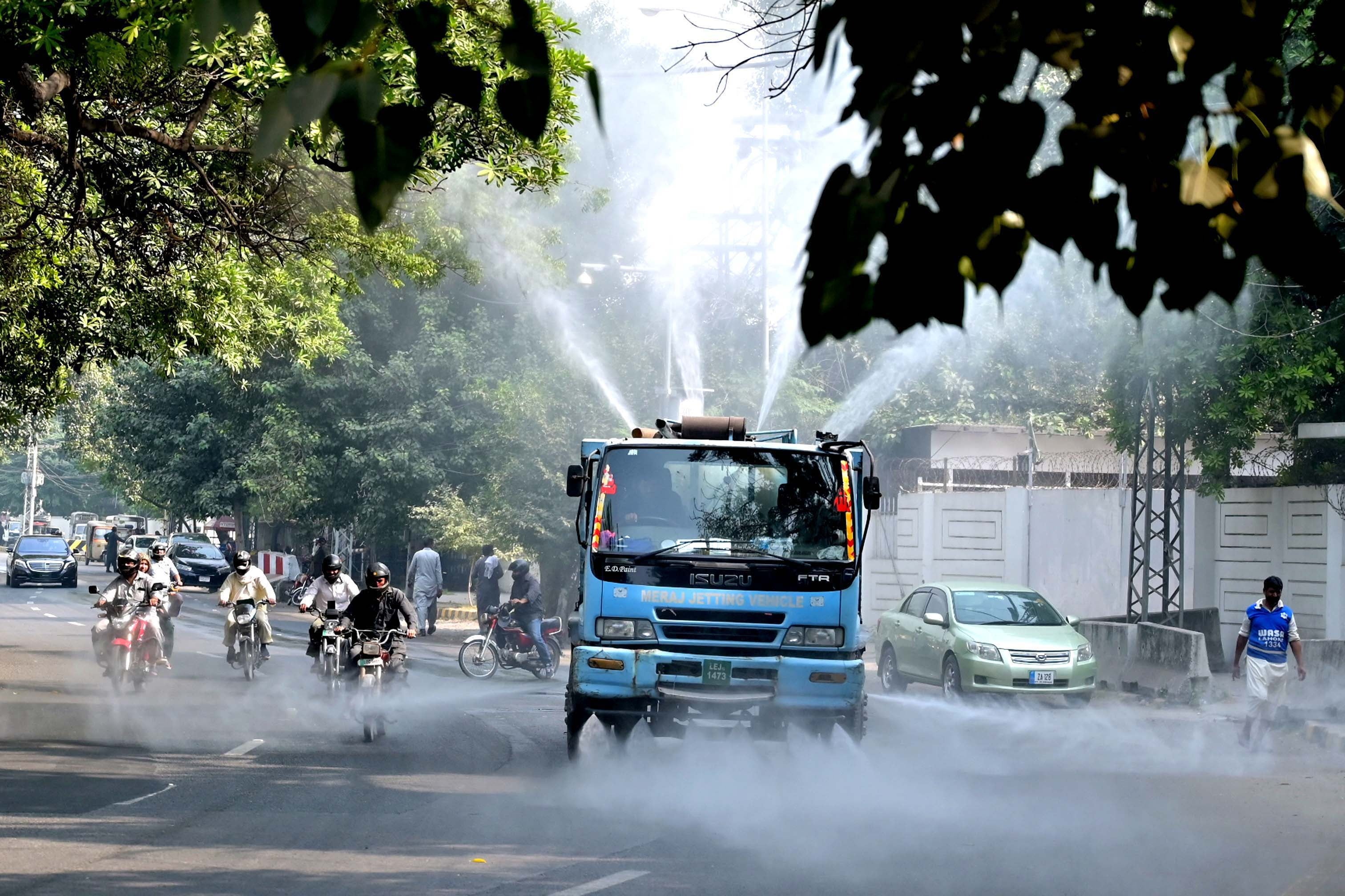 Municipal workers spray water on roads in Lahore to reduce smog effects