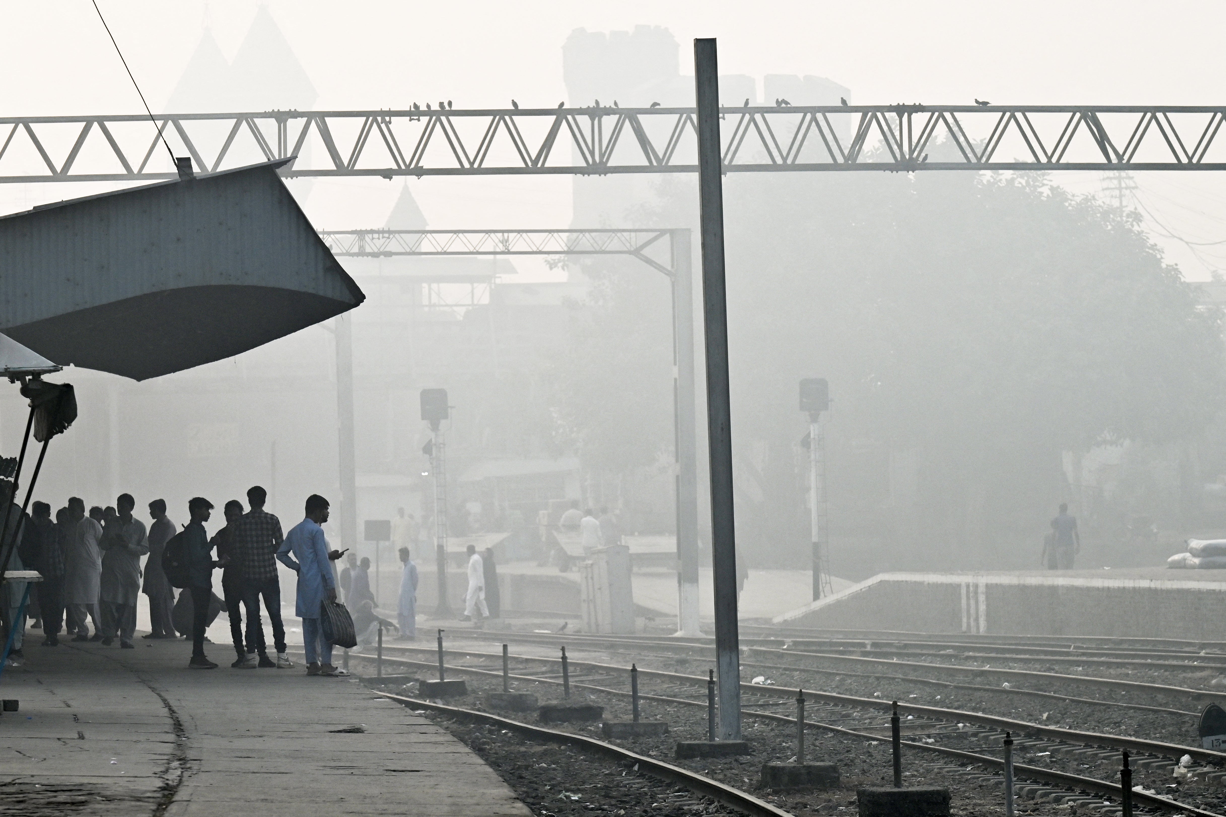 Passengers wait for a train at a railway station amid smoggy conditions in Lahore on 3 November 2024