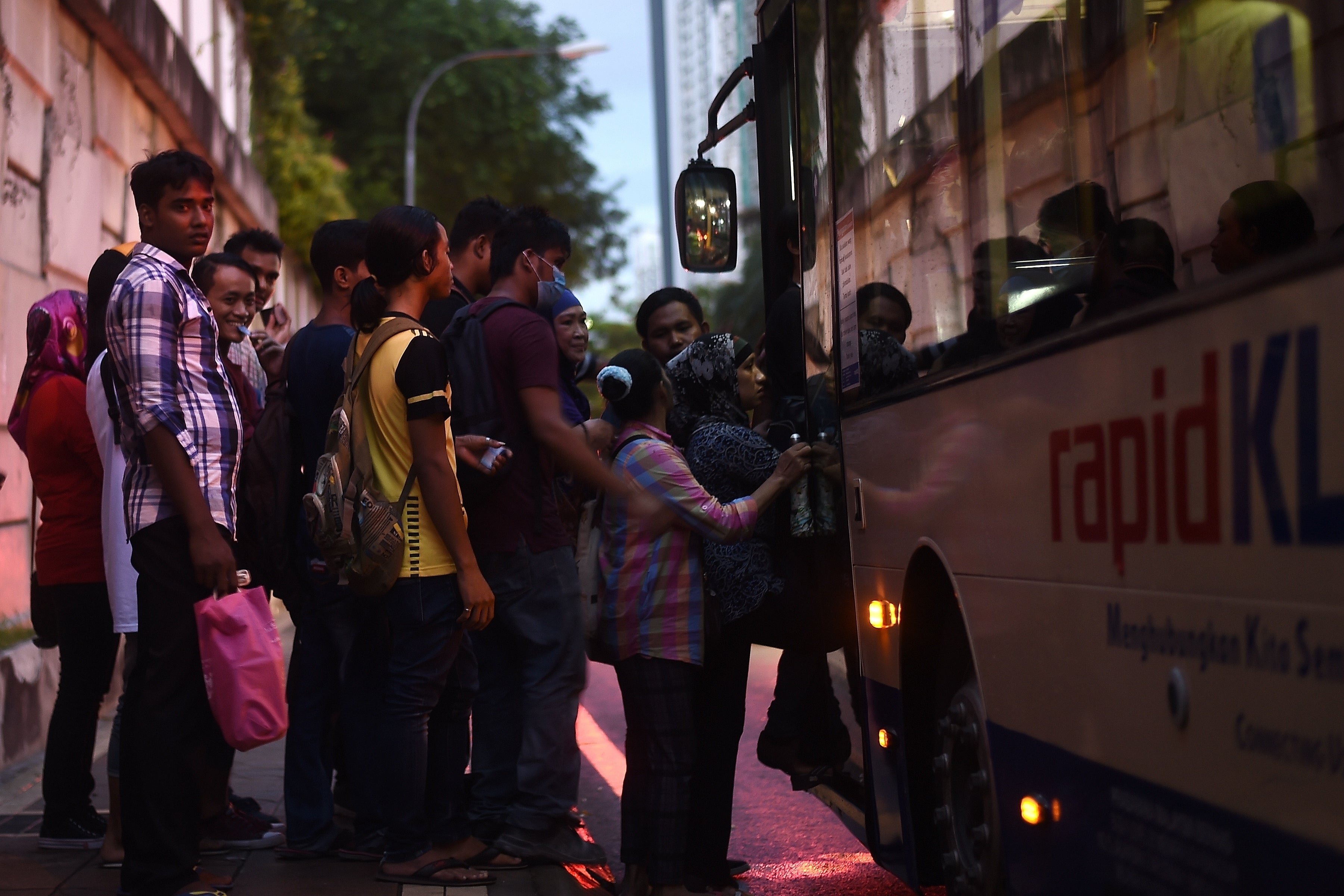 Representational: Malaysians stand in a queue as they board a public transport bus at dusk in Kuala Lumpur on 25 April 2017