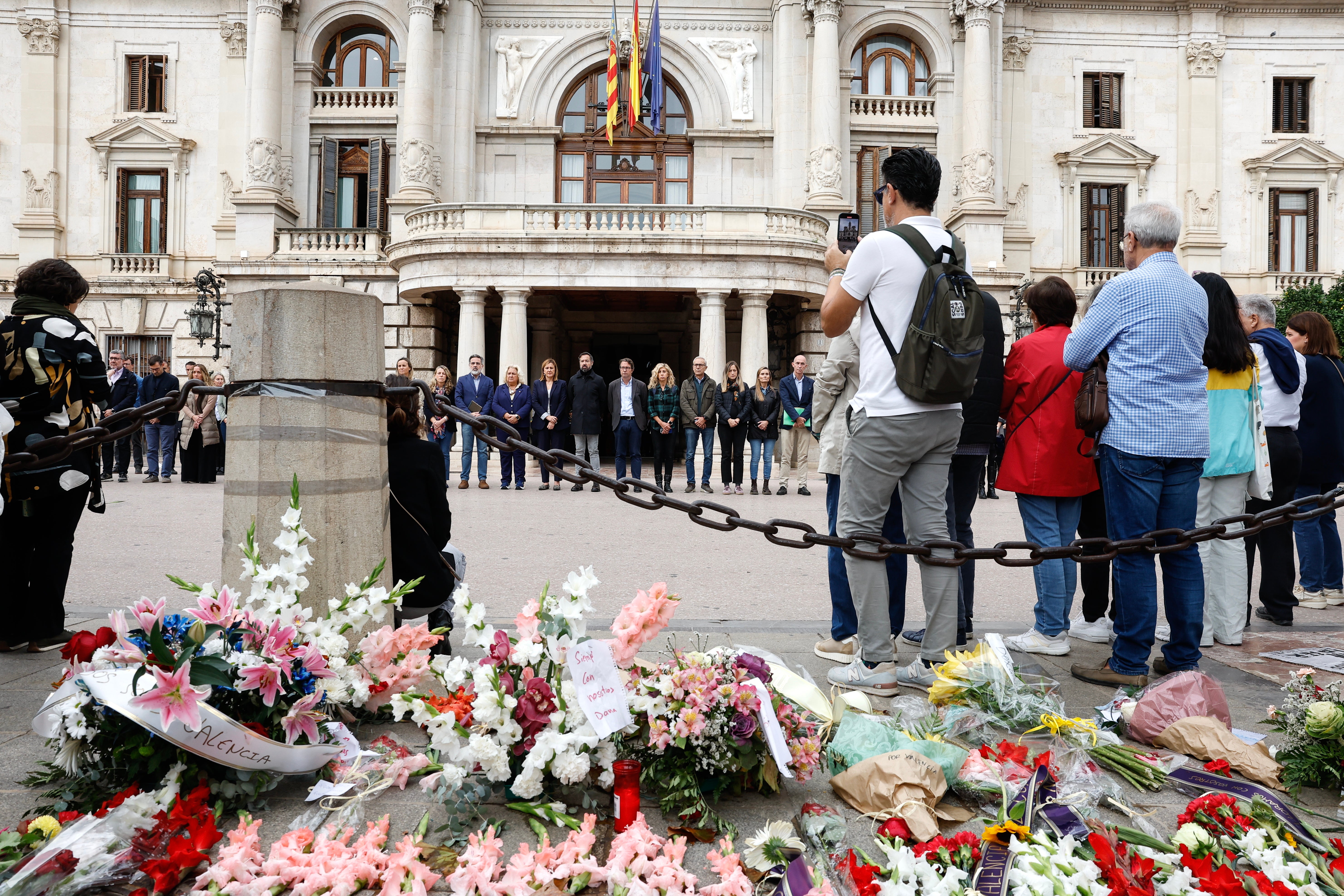 People observe a minute of silence for the flood victims next to floral tributes in front of Valencia City Hall, in Valencia, Spain,