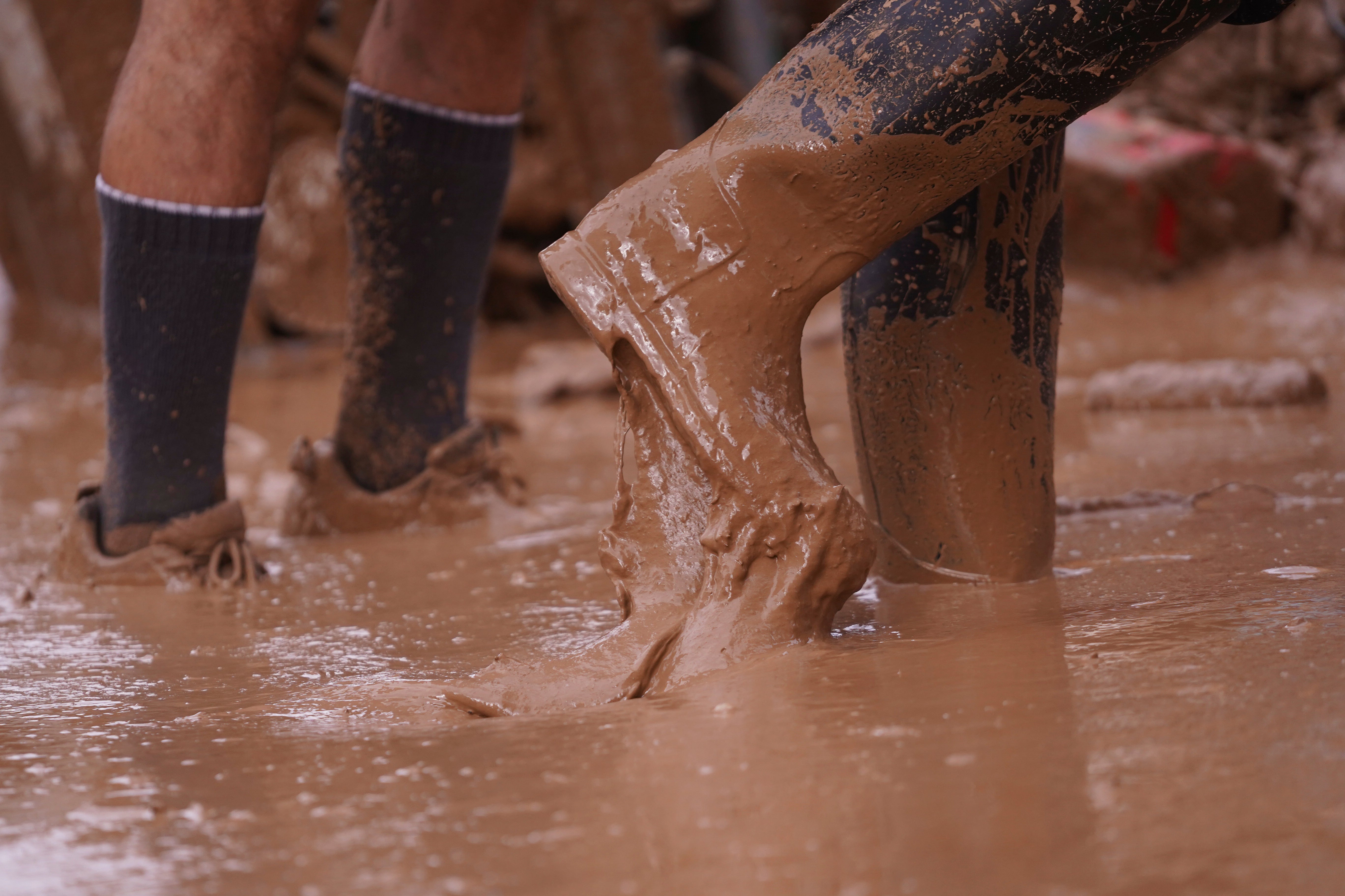 People walk in the mud after floods in Paiporta, near Valencia, Spain