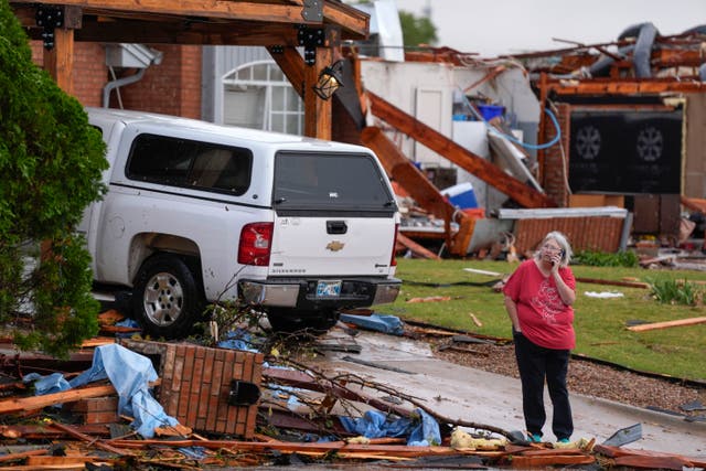 <p>A woman stands outside a damaged home after a tornado in Oklahoma City, Oklahoma, on Sunday. More than 18,000 Oklahoma customers were left without power on Monday, with more storms expected to hit the area. </p>