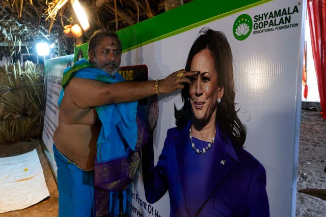 <p>A priest puts a ‘tilak’, a forehead mark worn by Hindus, on a photograph of Democratic presidential nominee Kamala Harris during special prayers for her victory in the US elections</p>